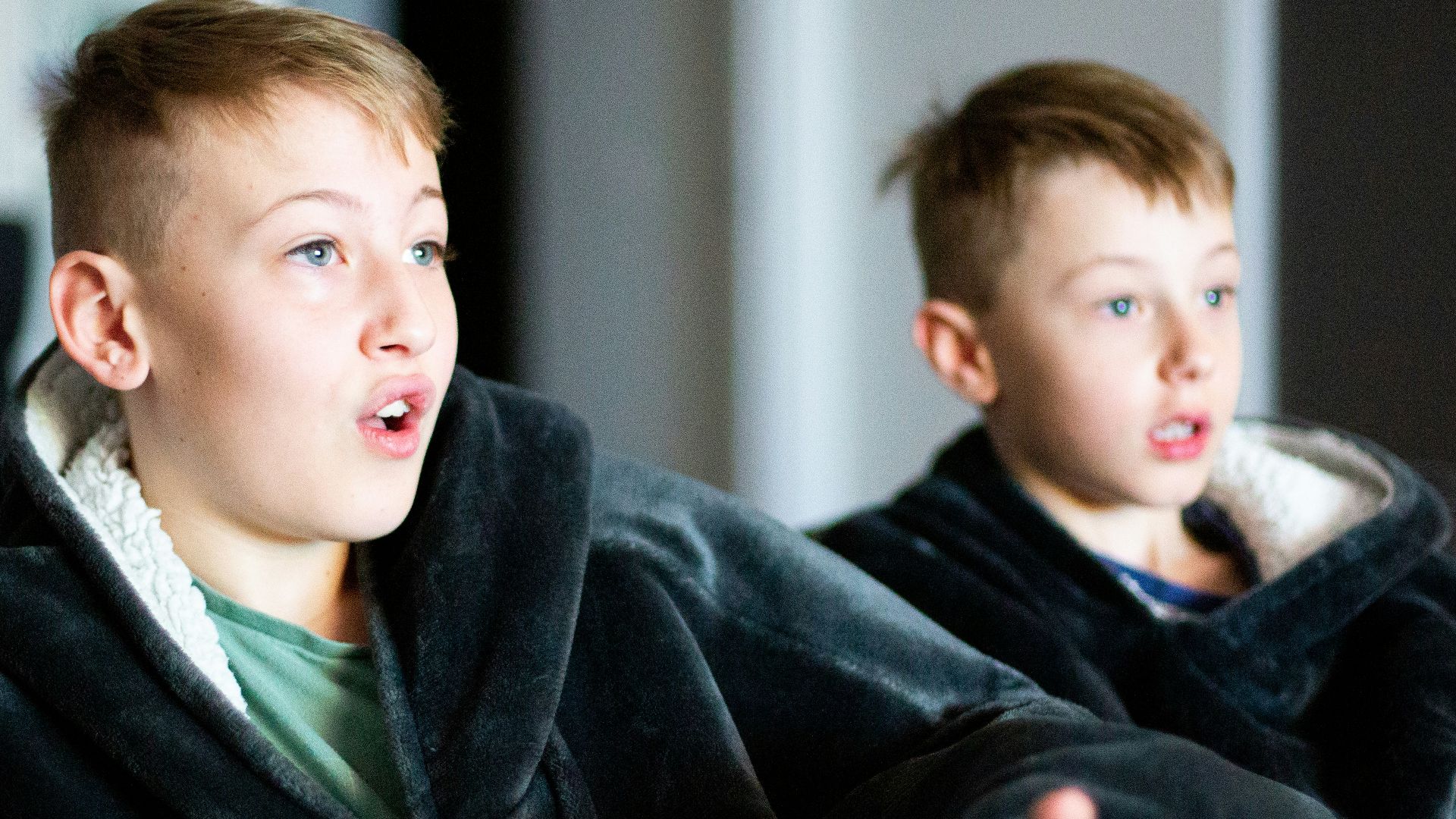 two young boys sitting on a couch playing a video game