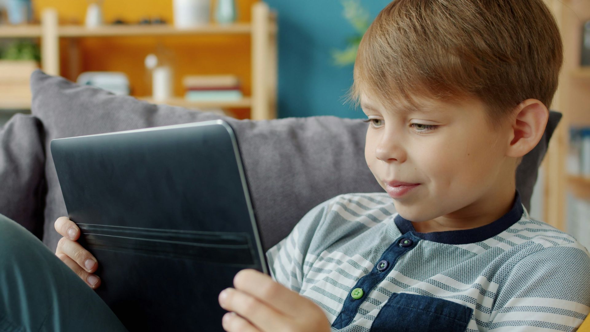 Young boy using a tablet on a couch