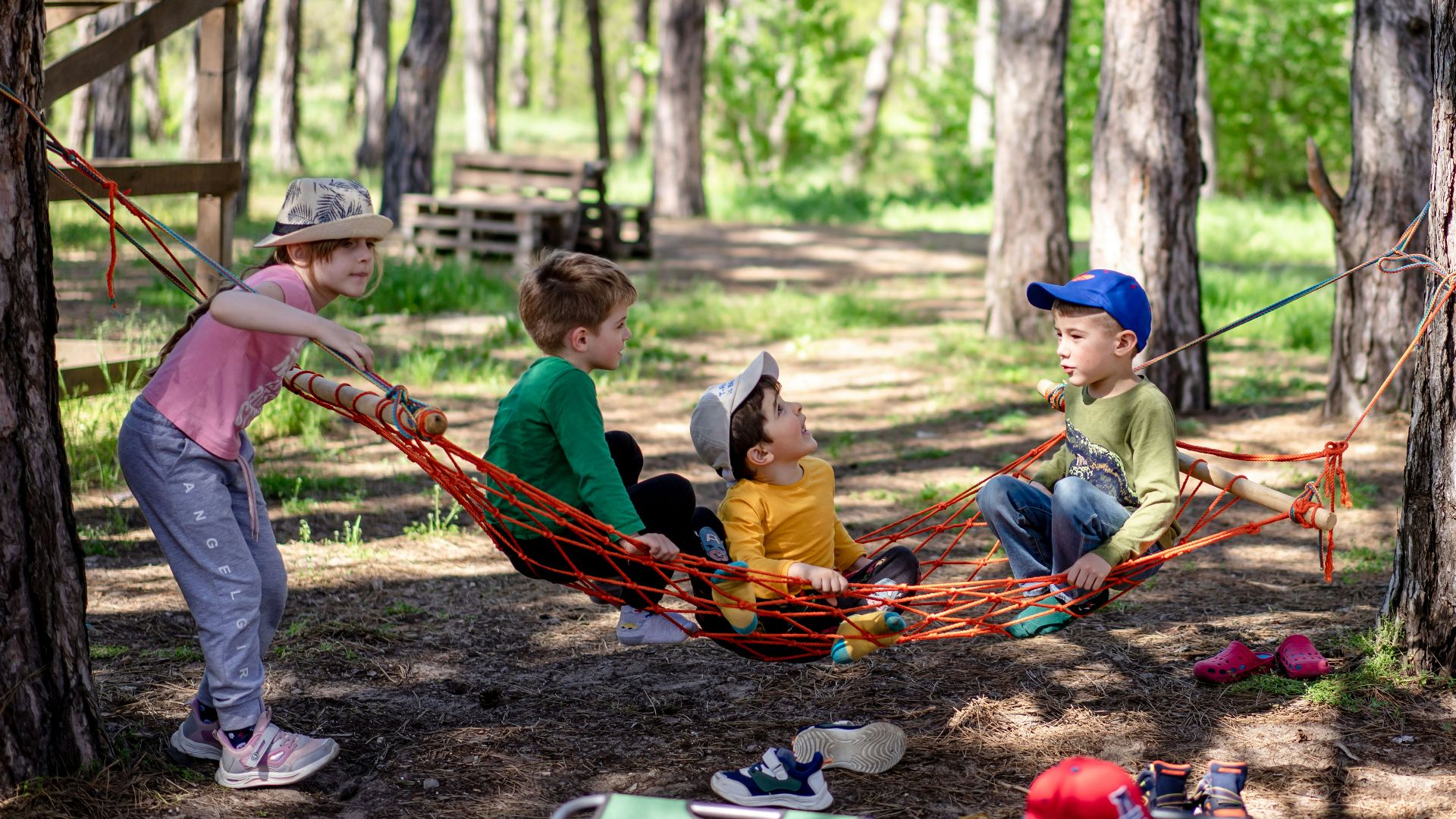 a group of kids sitting in a hammock in the woods