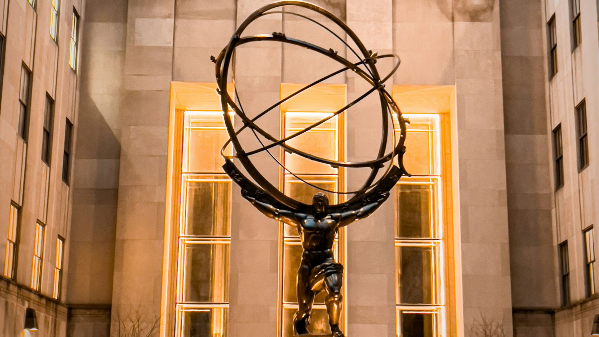 a statue of a person holding a globe in front of a building
