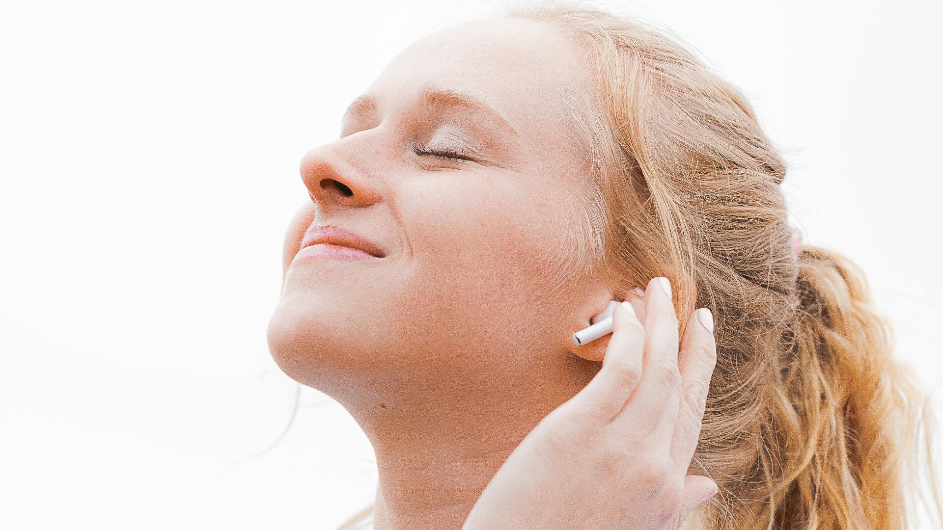 woman in white crew neck shirt covering her face with her hand