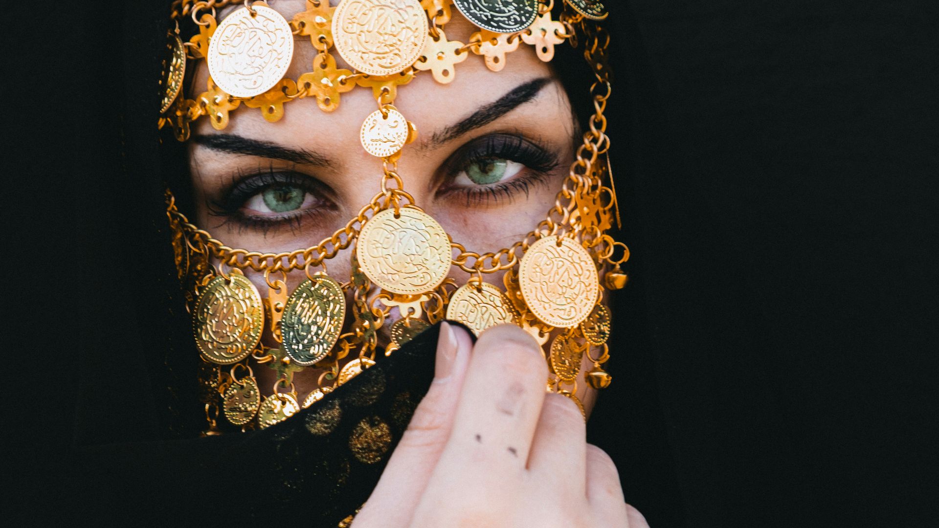 a woman wearing a black veil and a gold mask