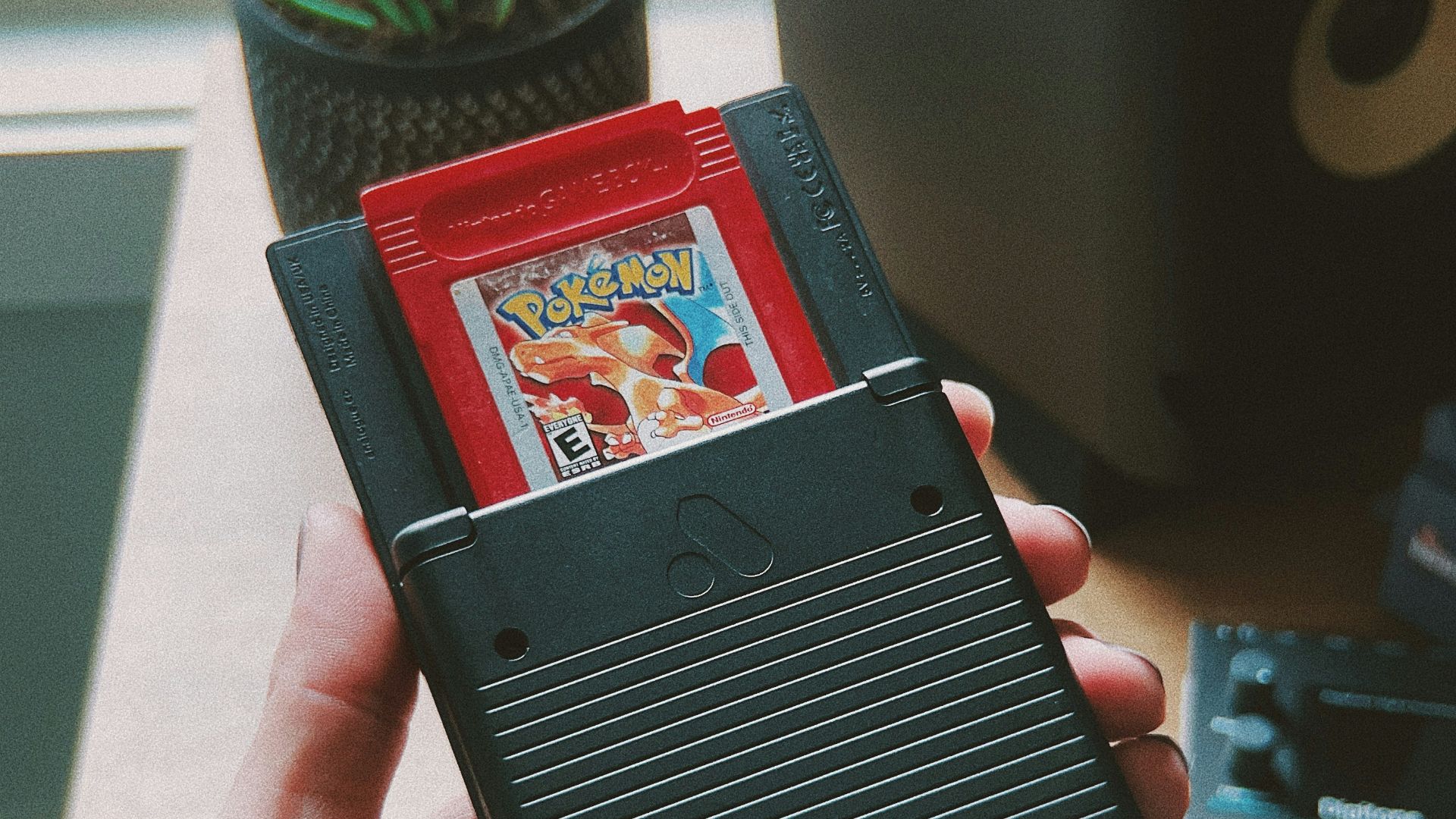 a person holding a nintendo gameboy in their hand
