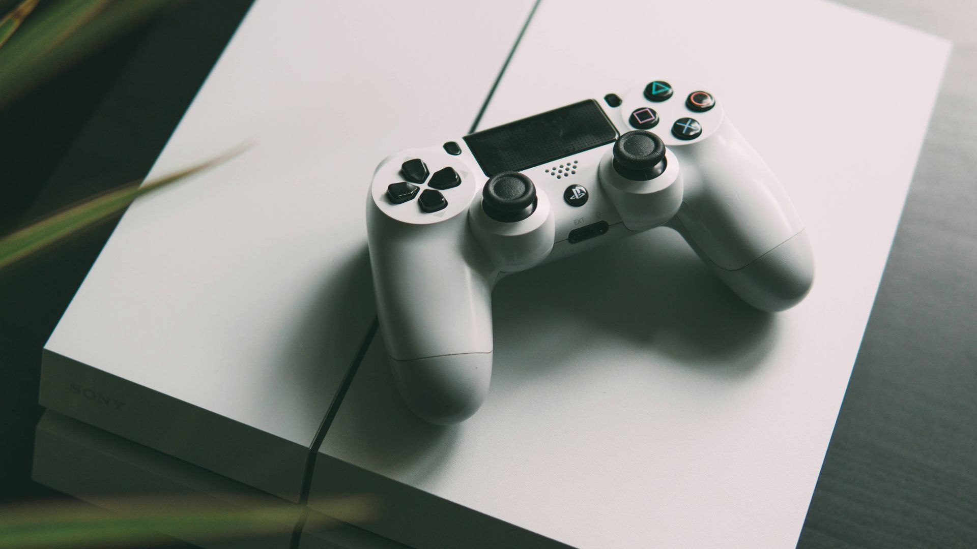 selective focus photography of white Sony PS4 console with wireless controller