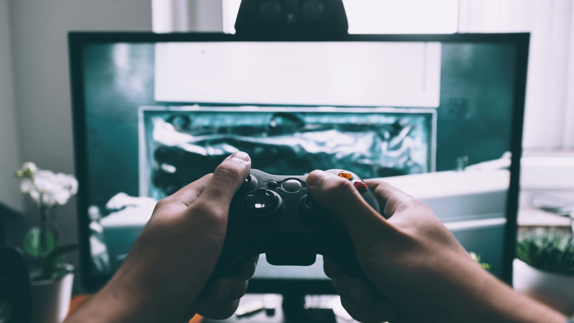 person holding game controller in-front of television