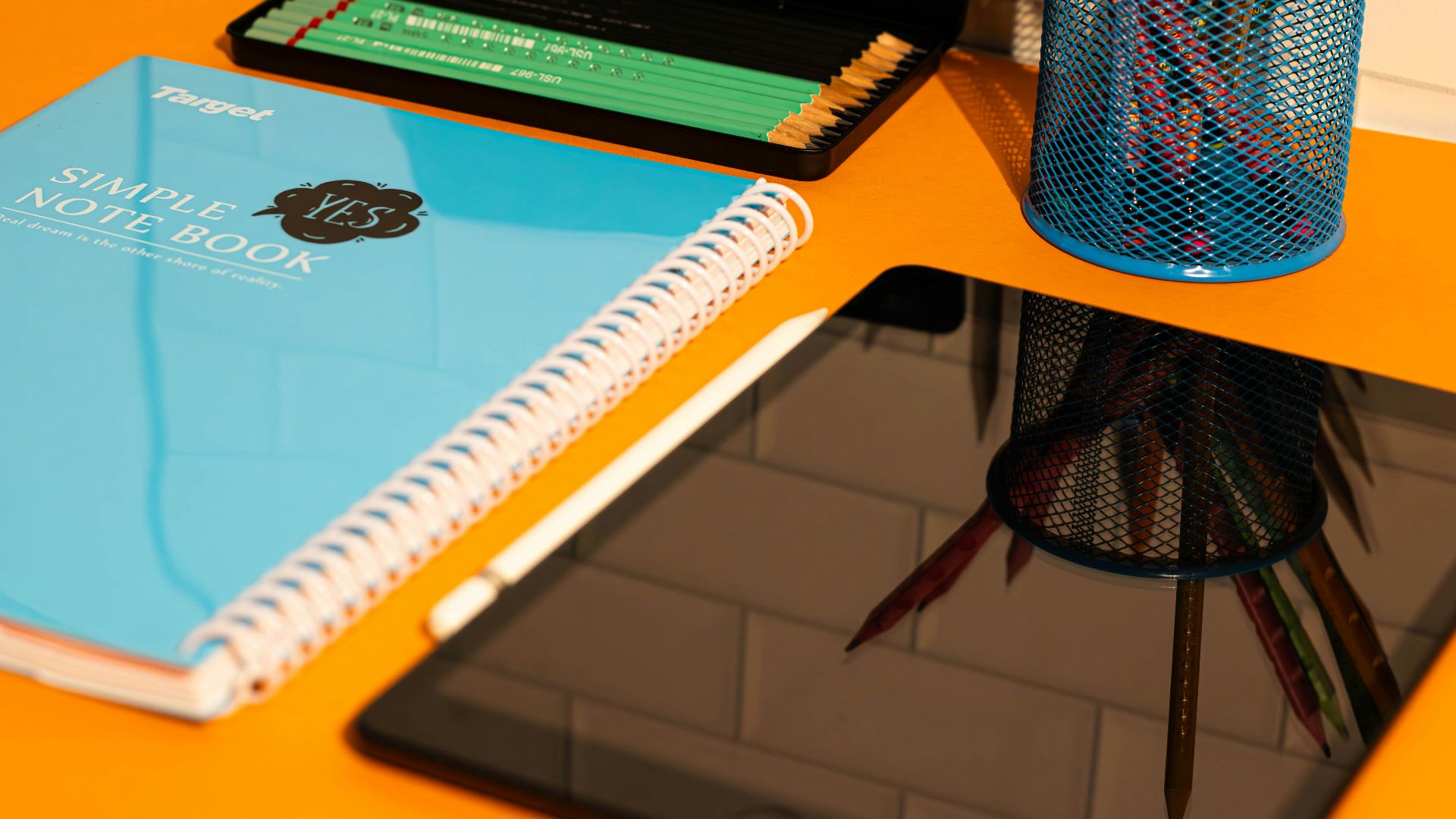 A desk with a laptop, notebook, and a cup of pencils