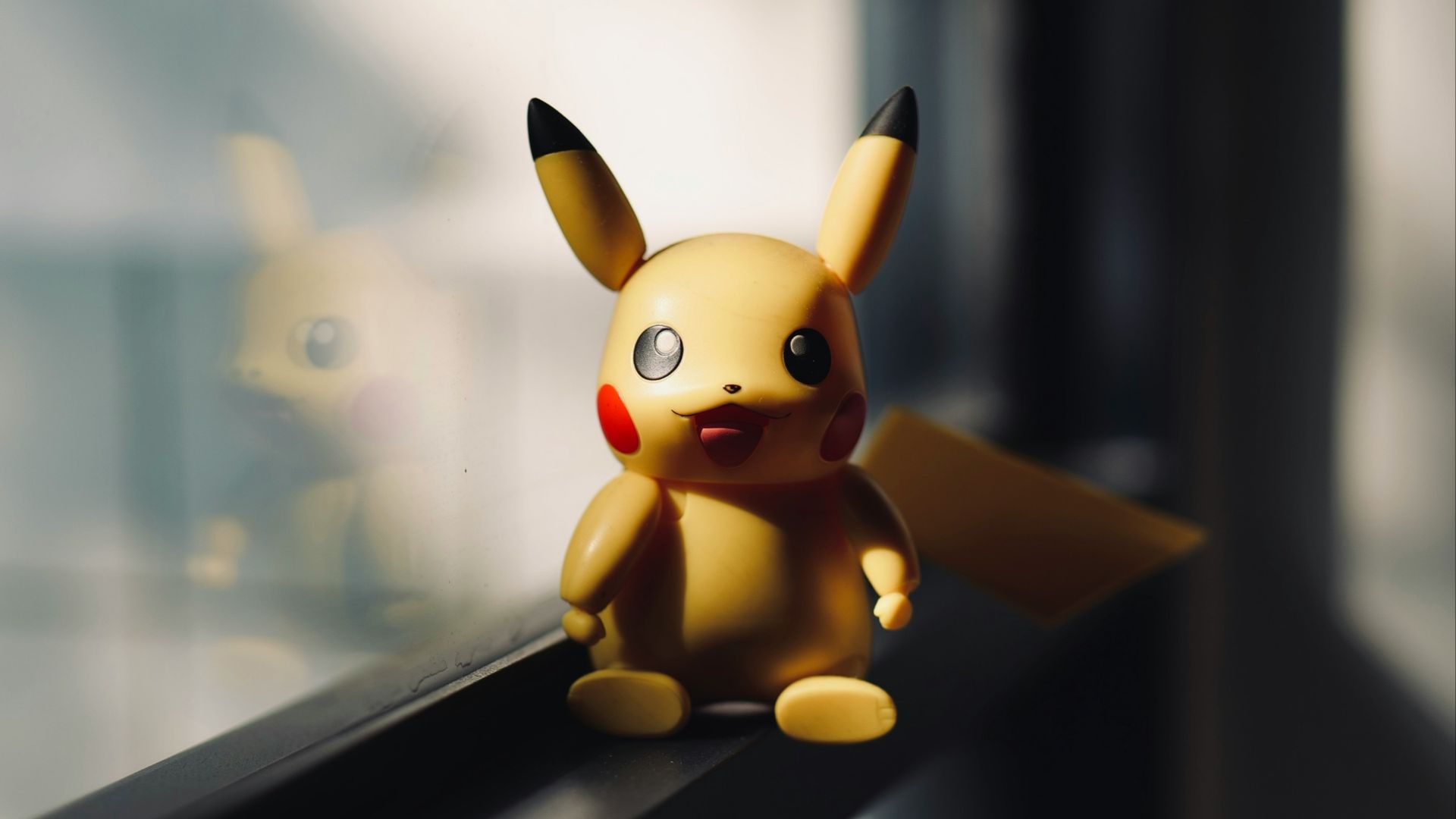 a toy pikachu sitting on a window sill
