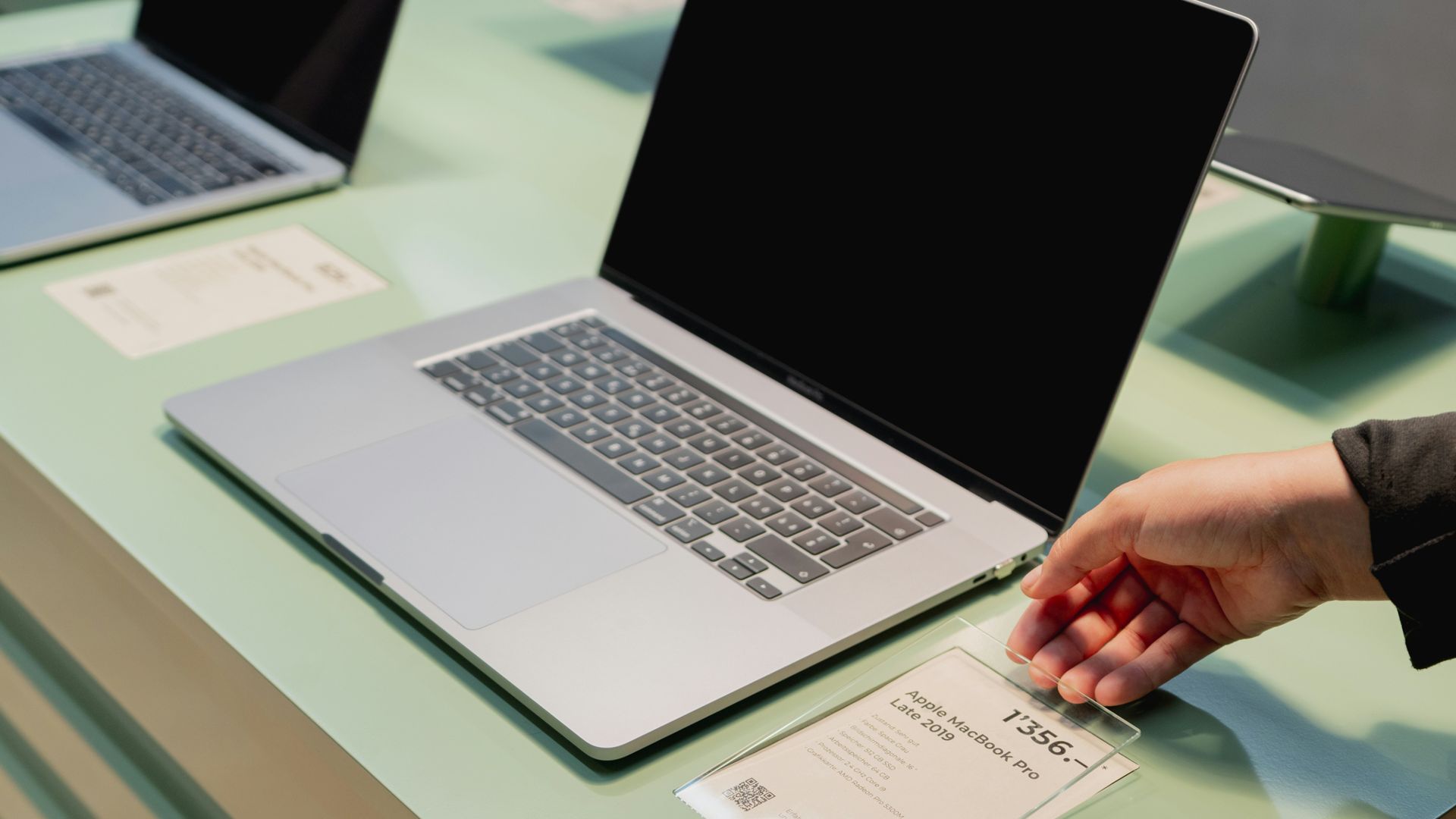 a person's hand on top of a laptop computer