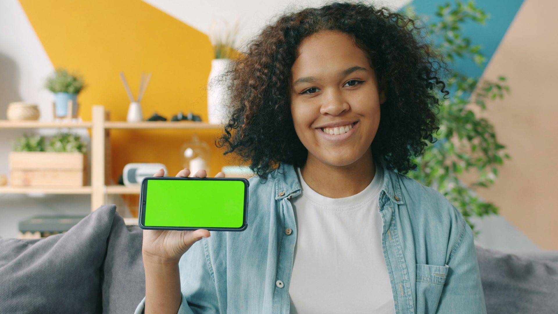 Young woman holding a smartphone with a green screen.