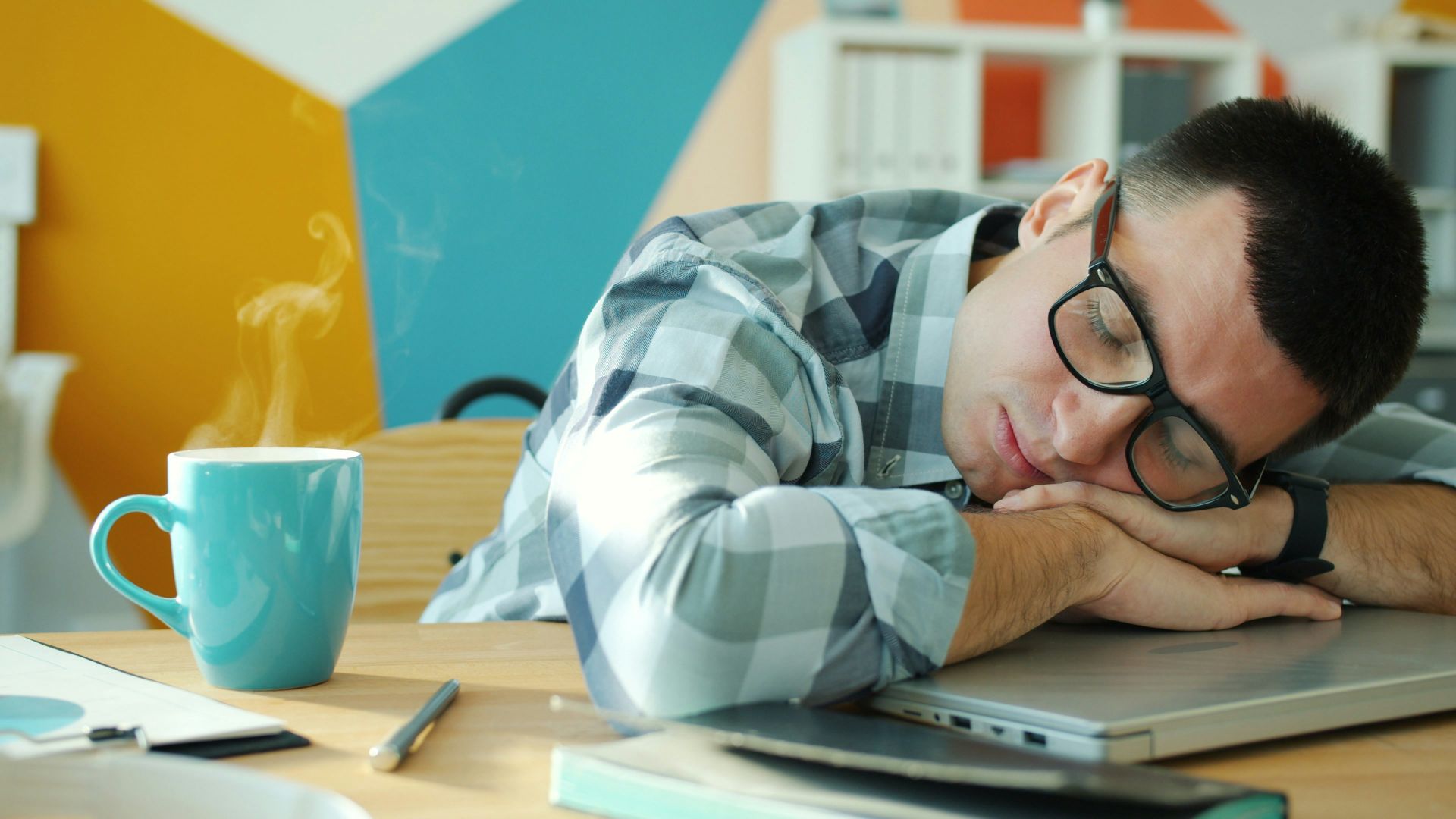Man sleeping at desk with coffee nearby