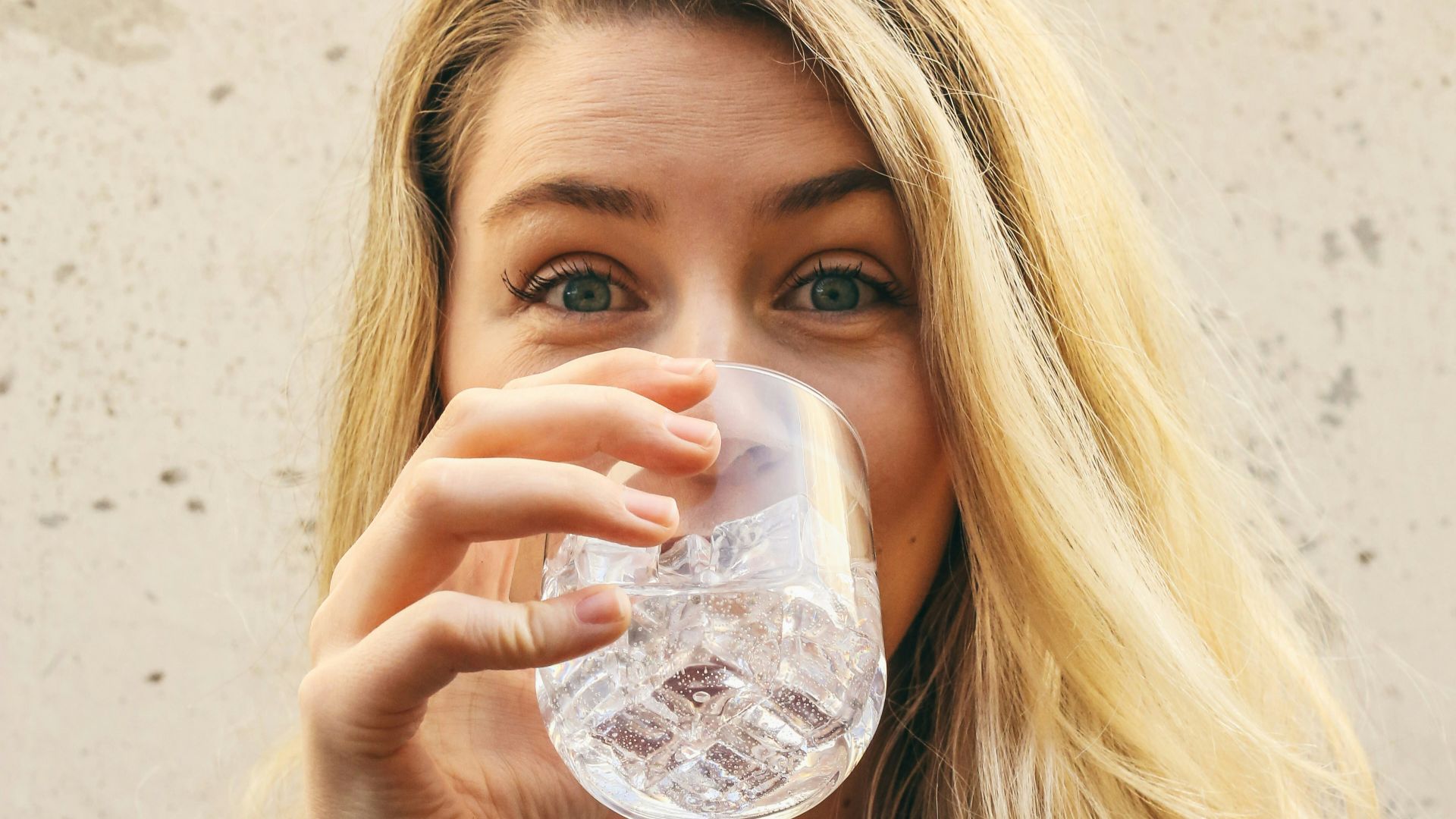 woman in white crew neck shirt drinking water