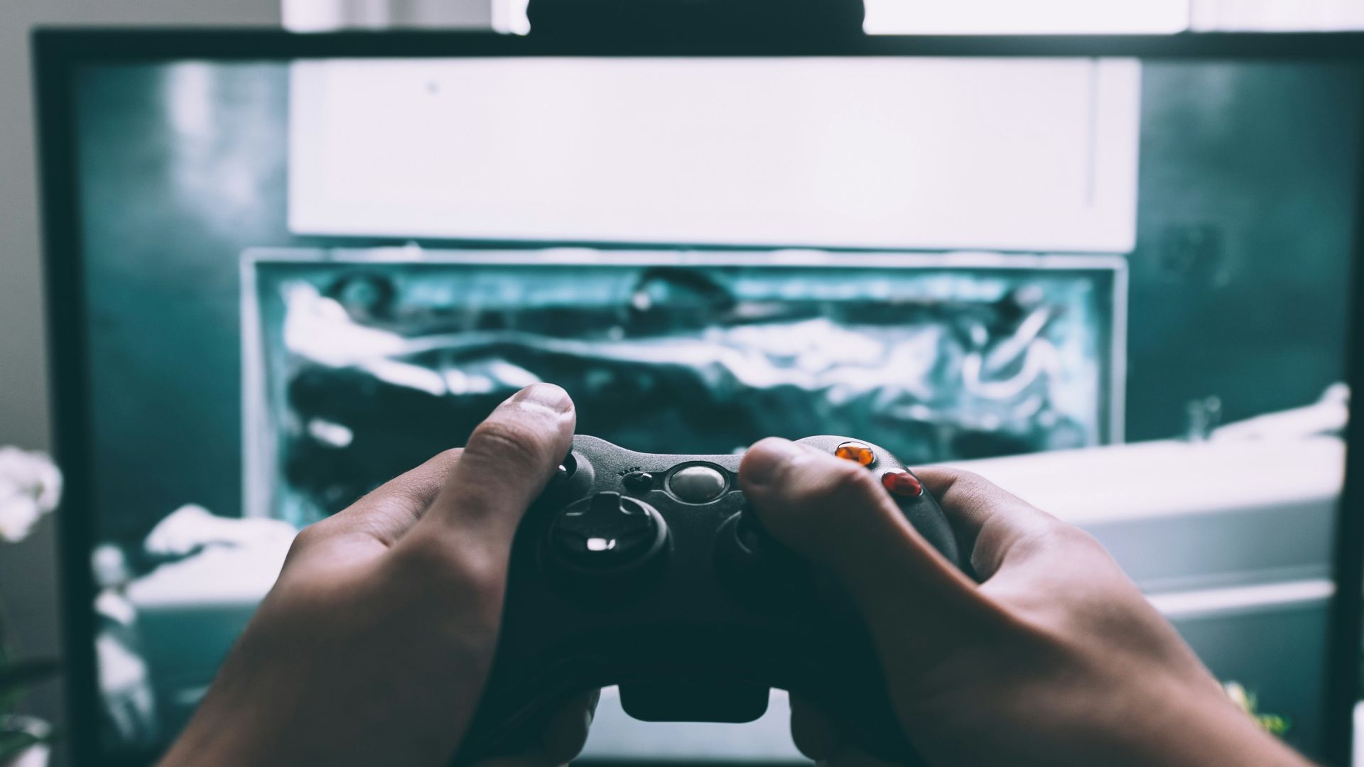 person holding game controller in-front of television