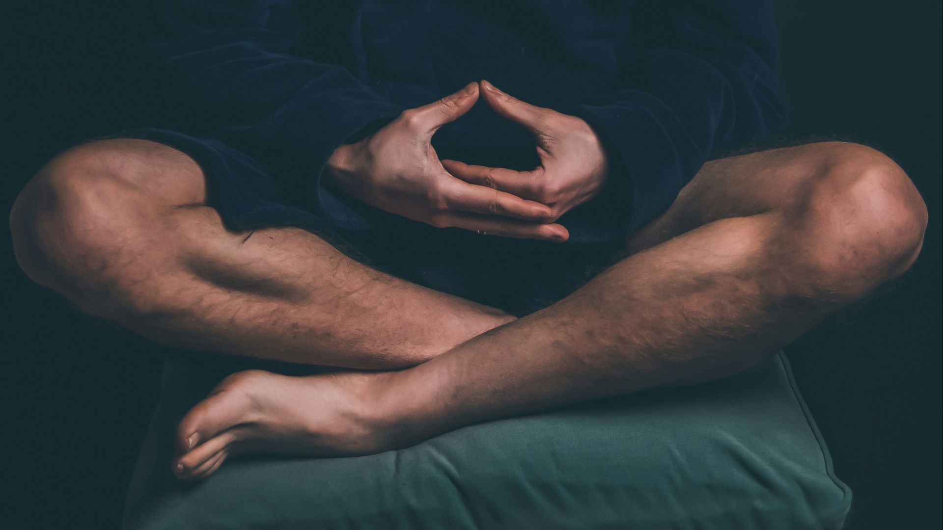 man in black hoodie sitting on black background