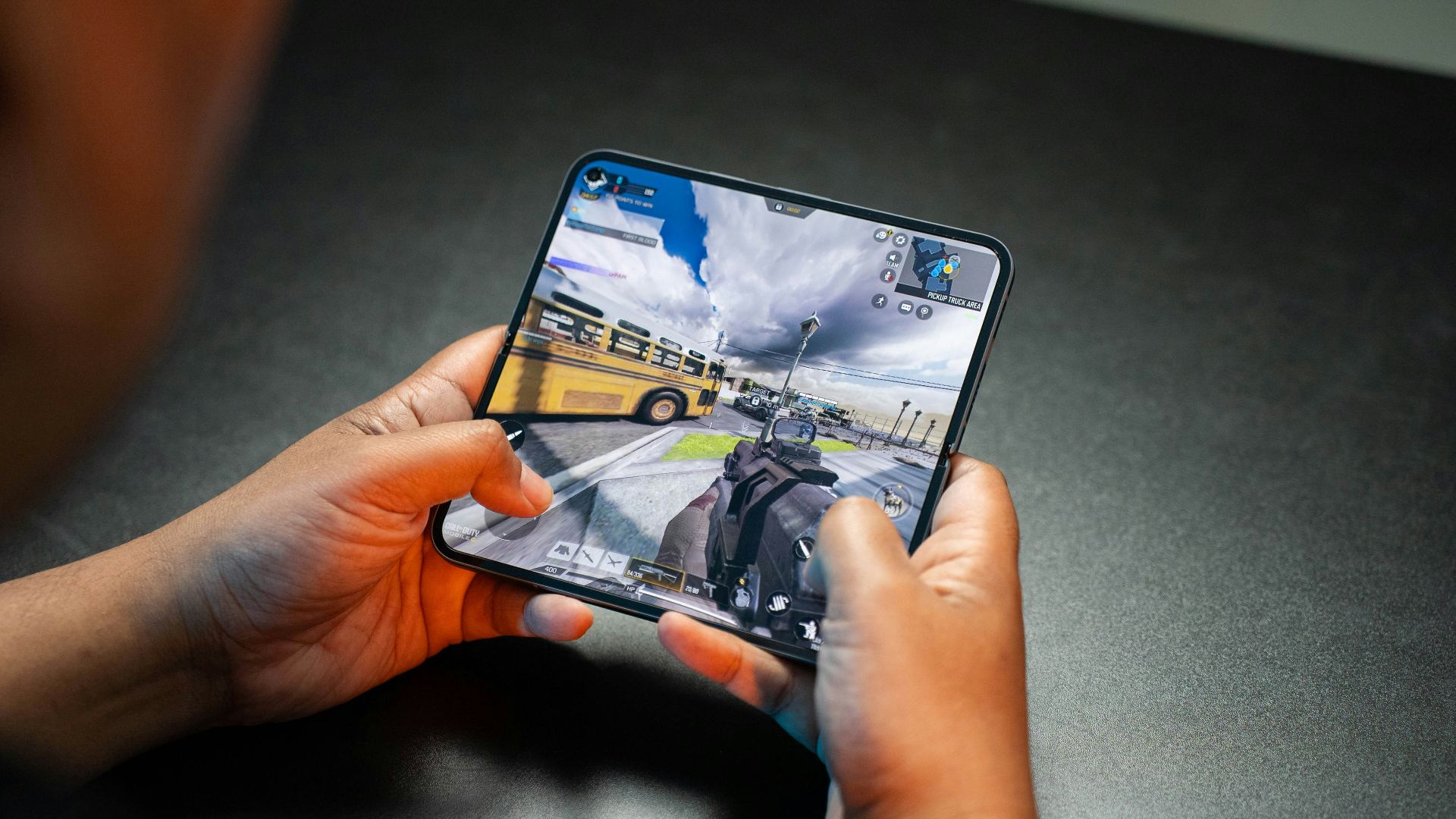 Person playing a video game on a foldable phone.