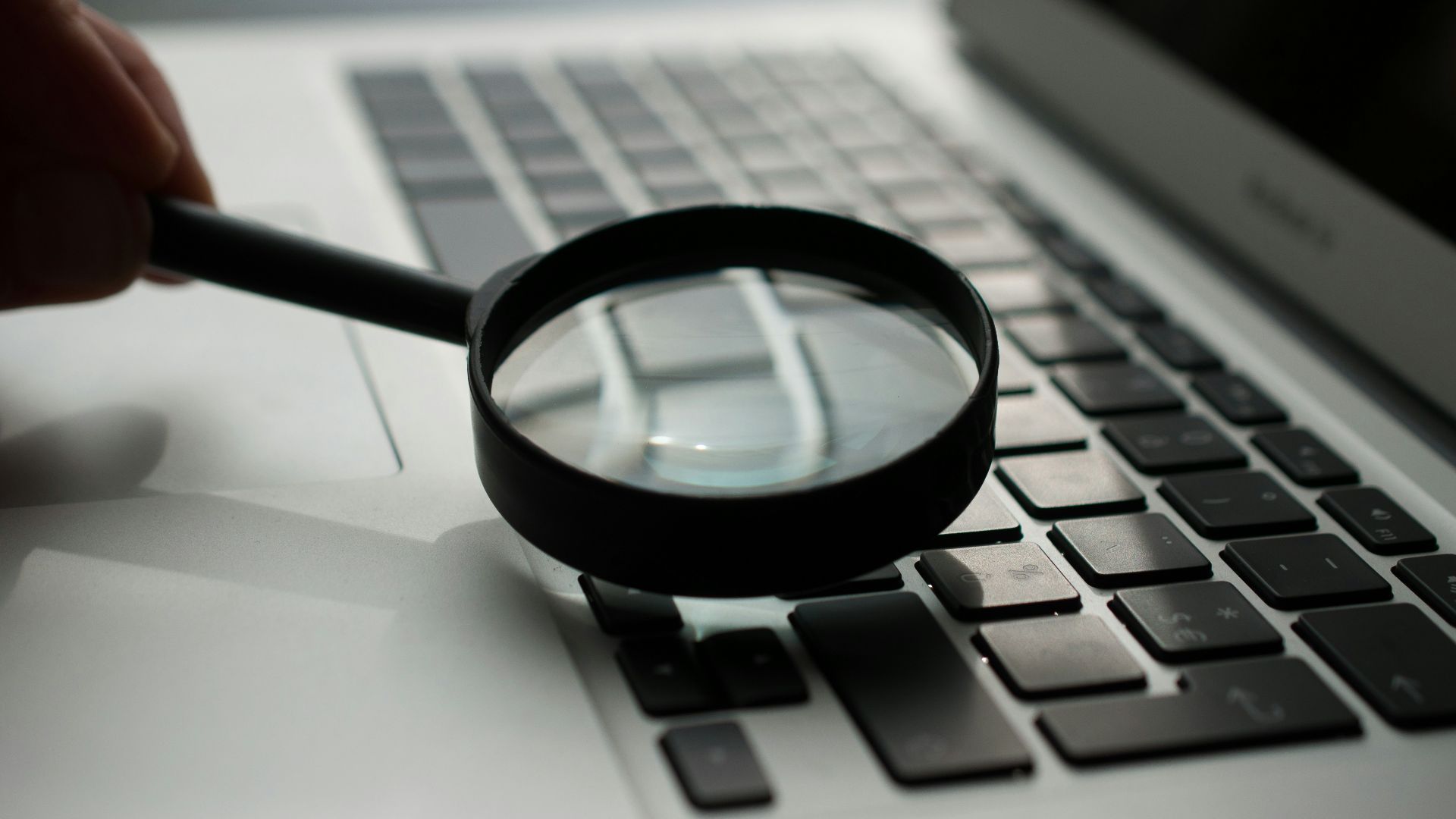 magnifying glass near gray laptop computer