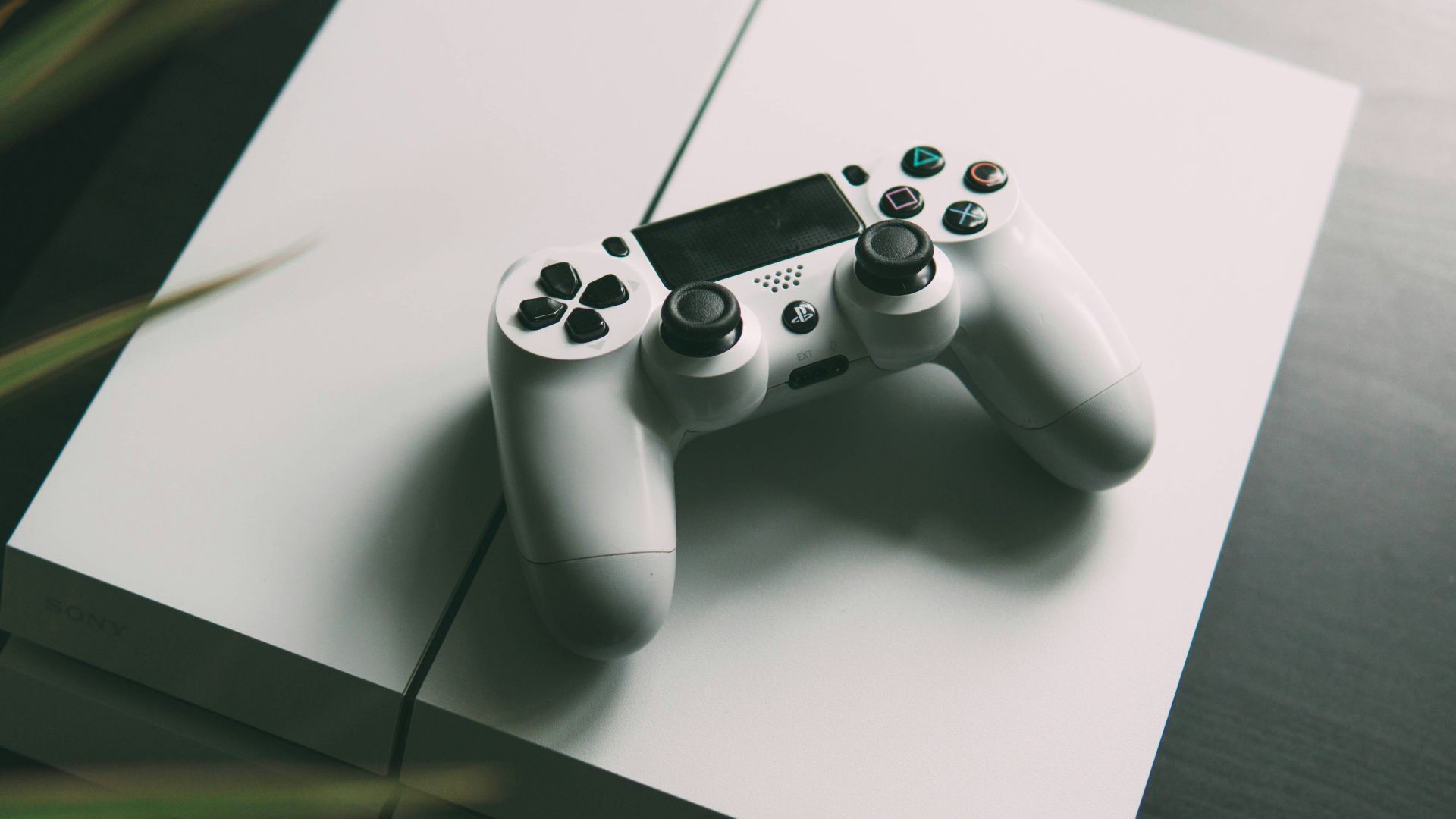 selective focus photography of white Sony PS4 console with wireless controller
