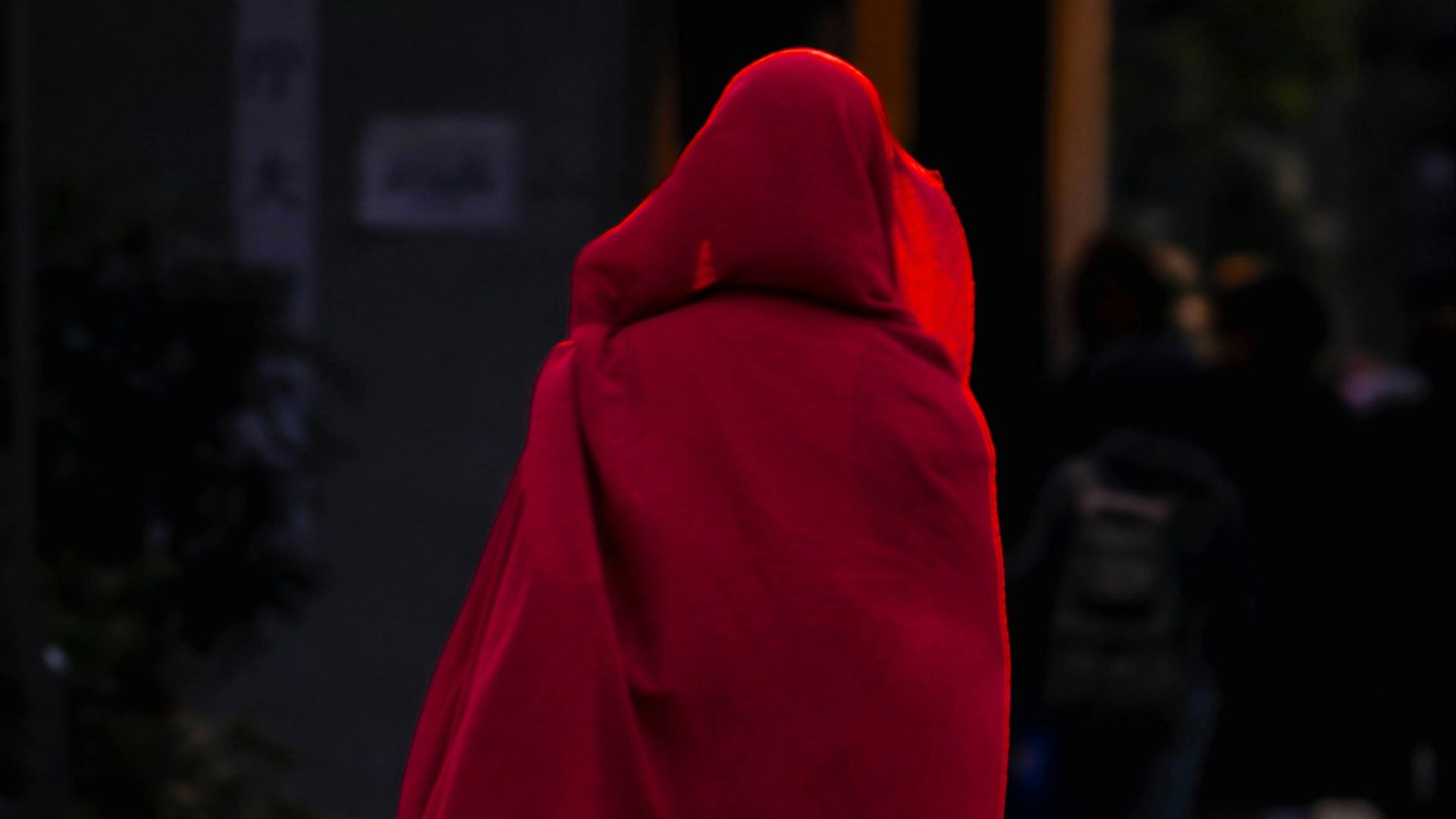 a person in a red cloak walking down a street