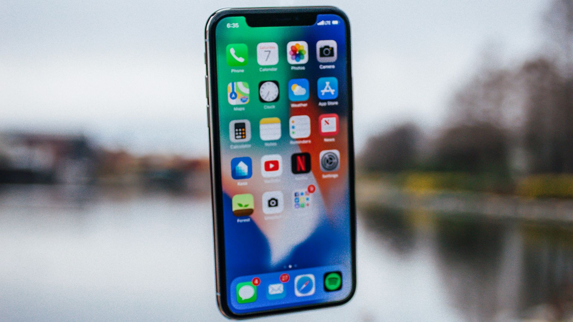 silver iPhone X floating over open palm