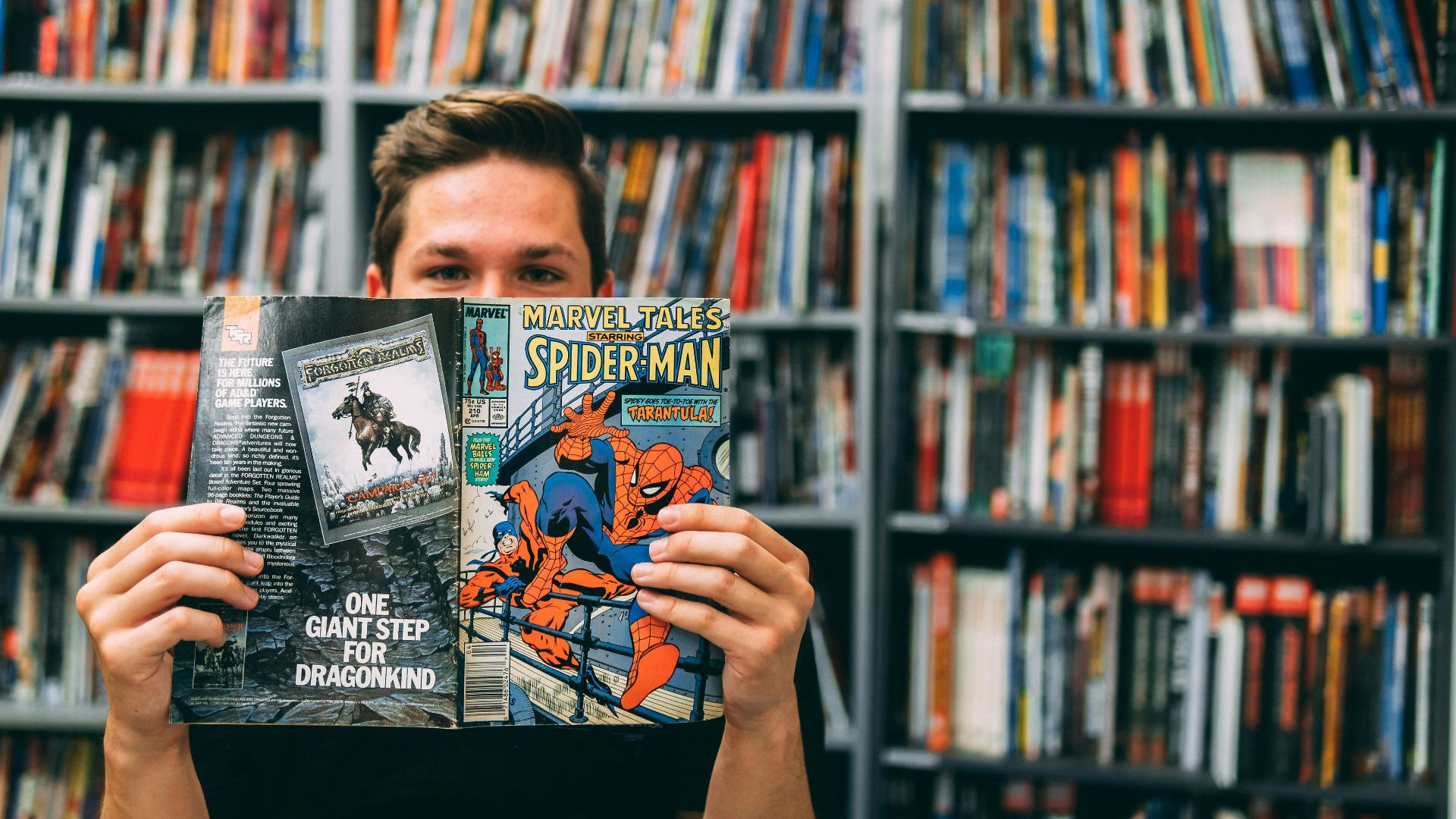 A man holding up a book in front of a library full of books