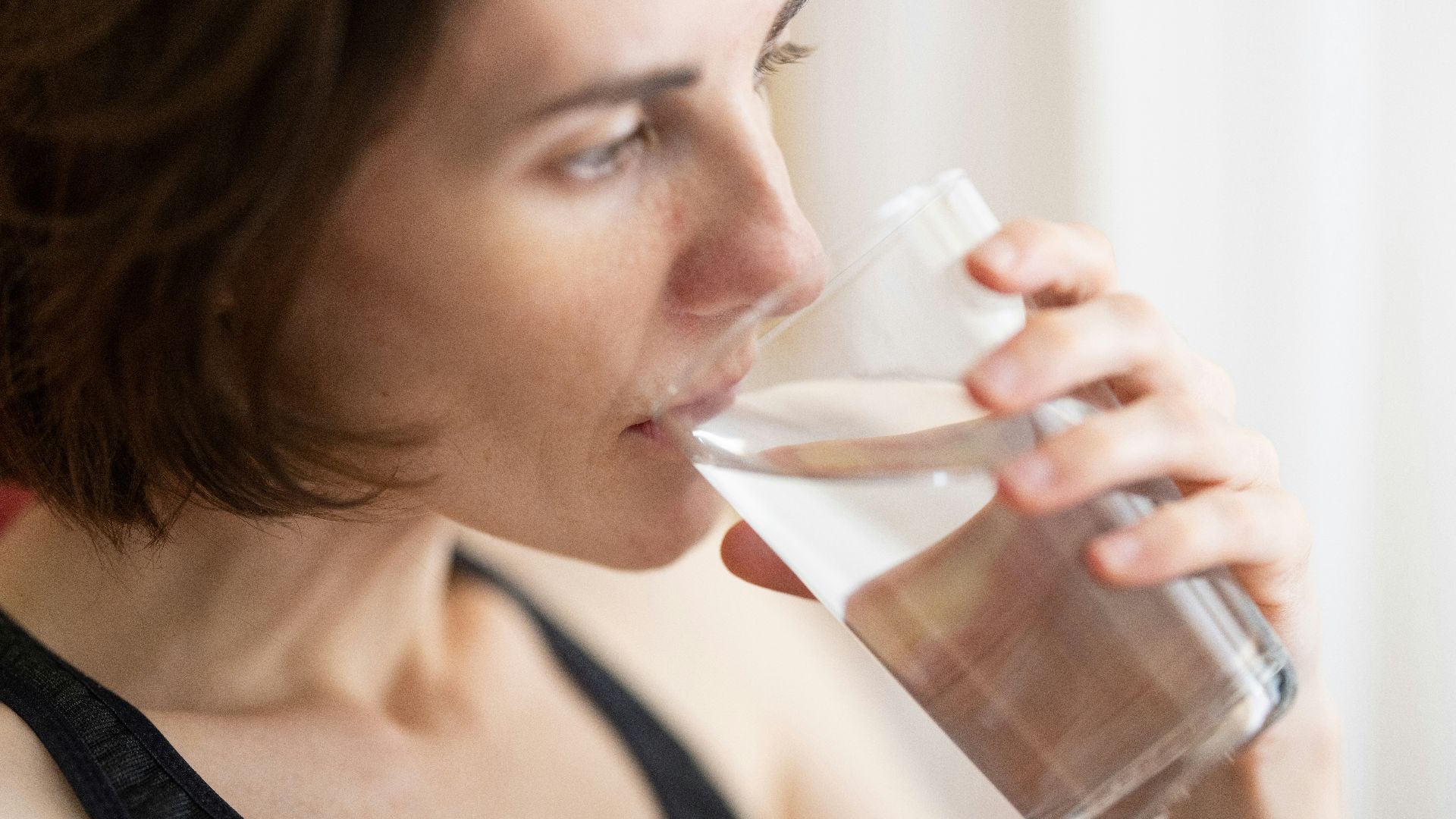 woman in black tank top drinking water