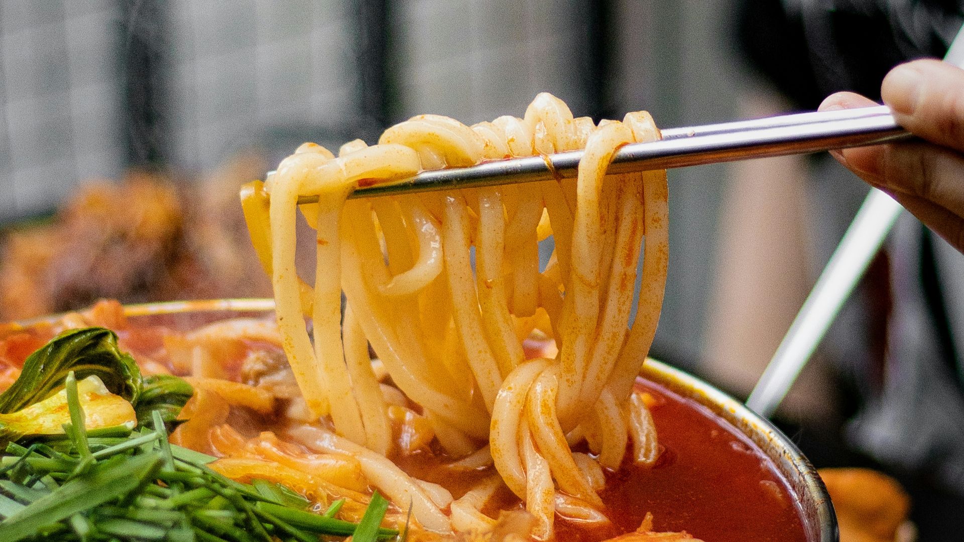 a person holding a spoon full of noodles