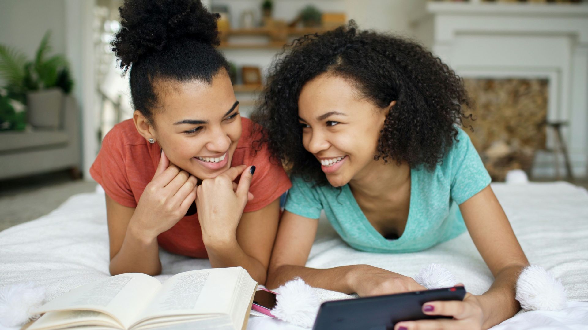 Two smiling young women looking at a smartphone.
