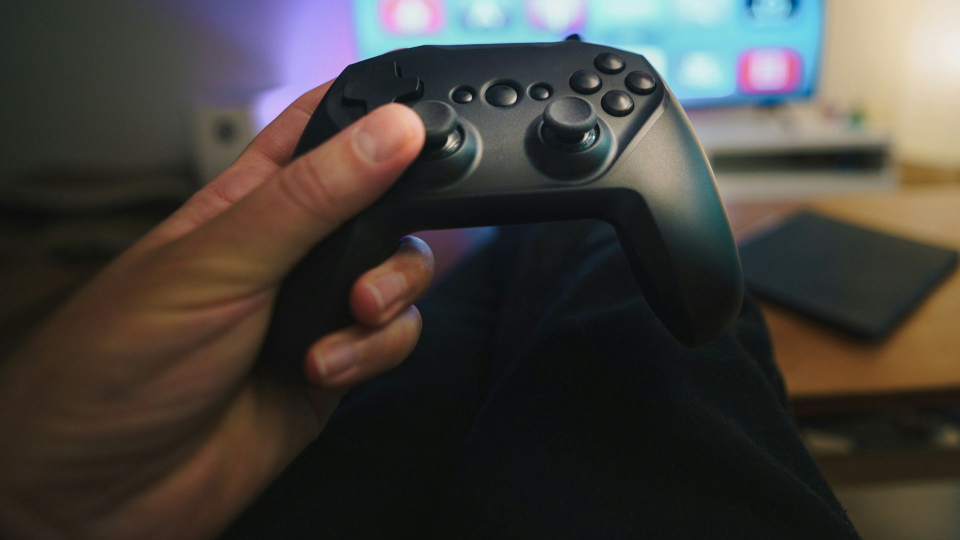 A person holding a video game controller in front of a computer