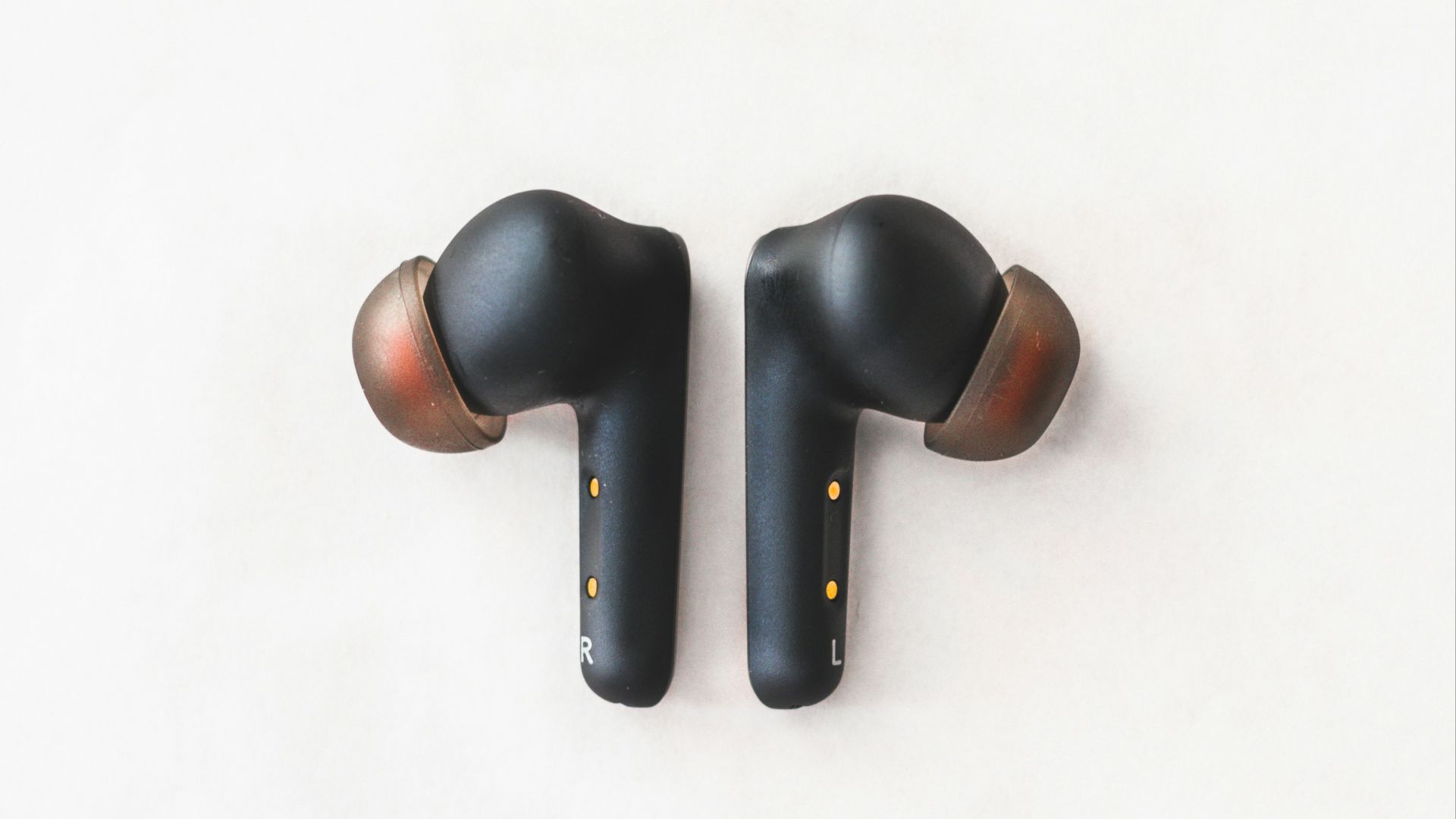 a pair of black ear buds sitting on top of a white surface