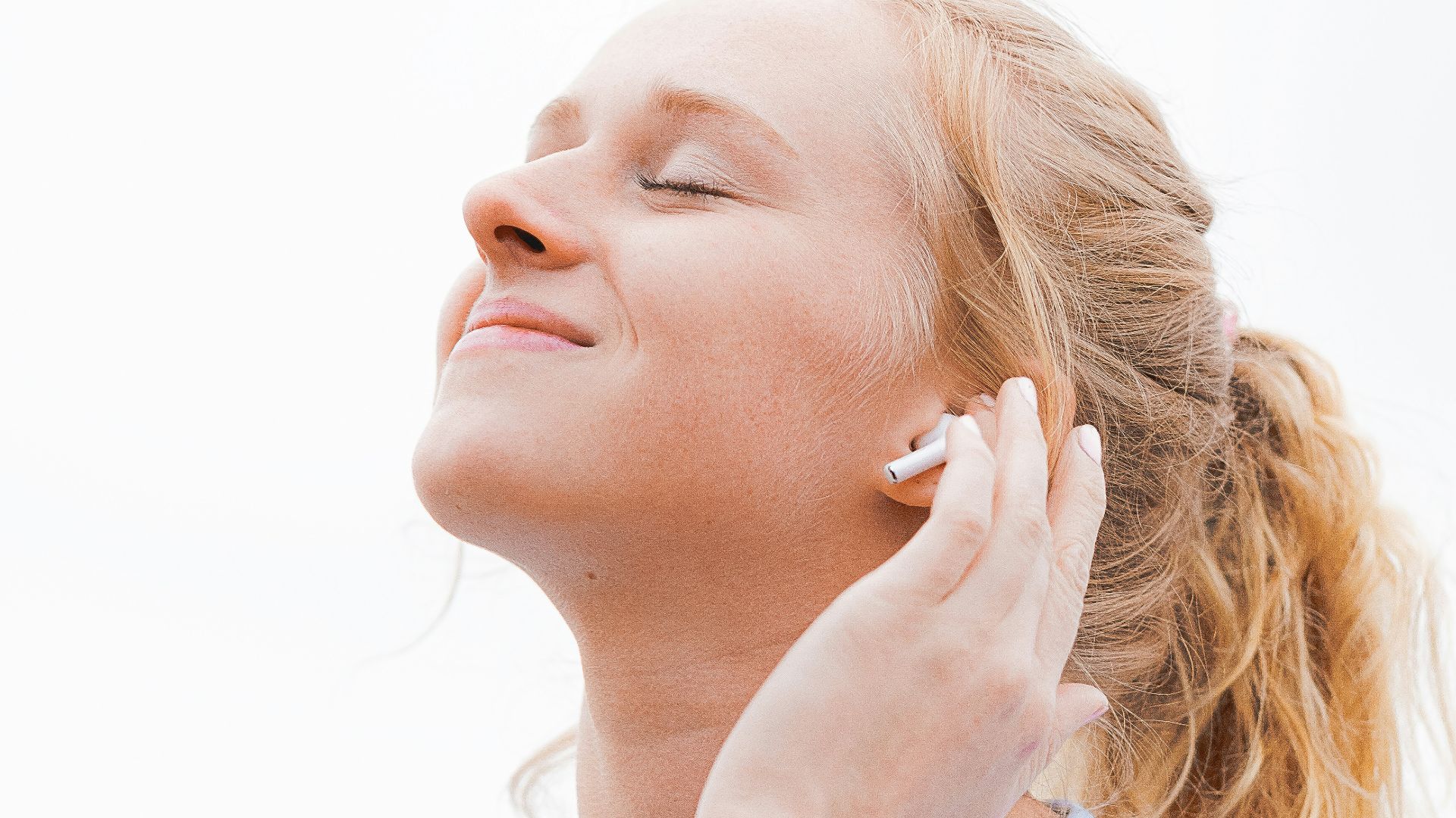 woman in white crew neck shirt covering her face with her hand