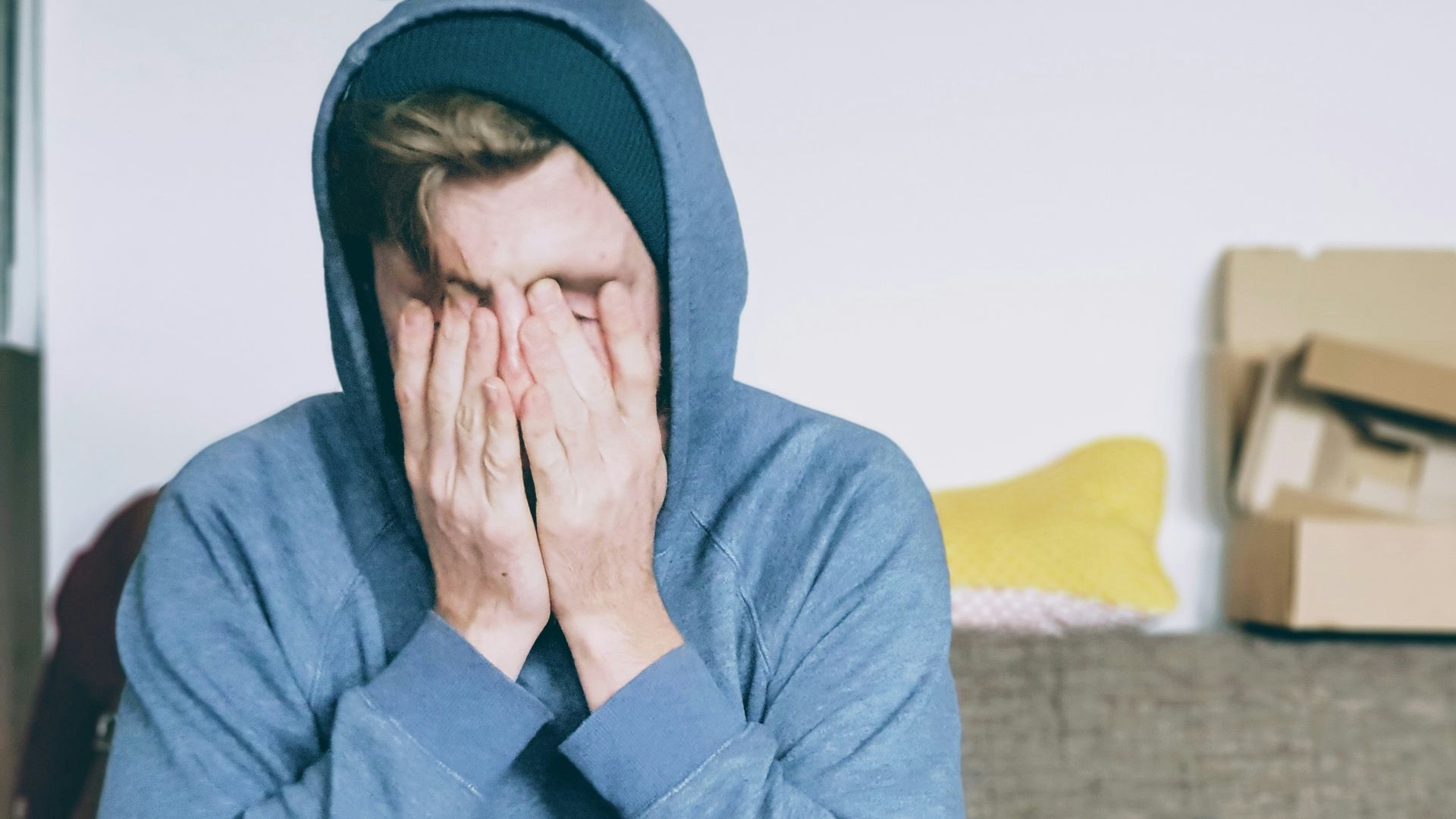 man covering face with both hands while sitting on bench