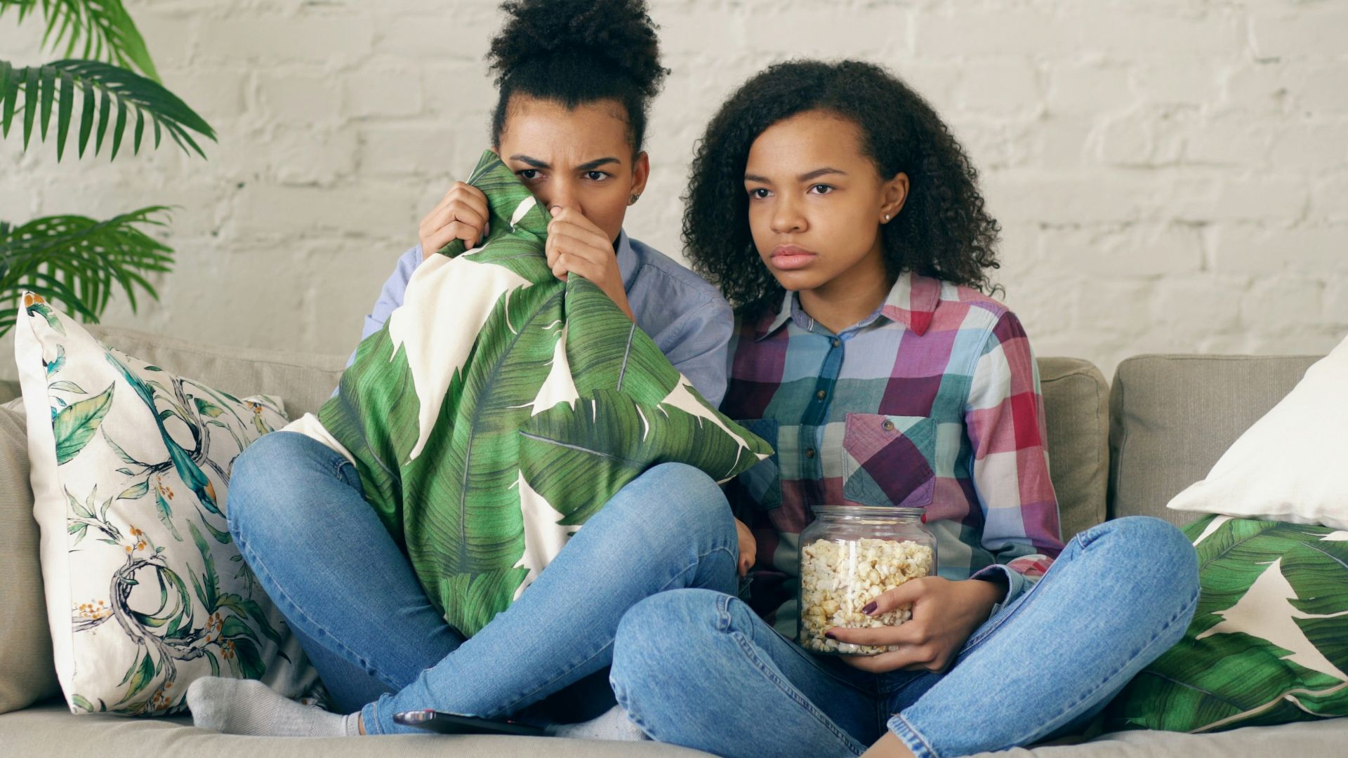 Two people watching tv, one holding popcorn.