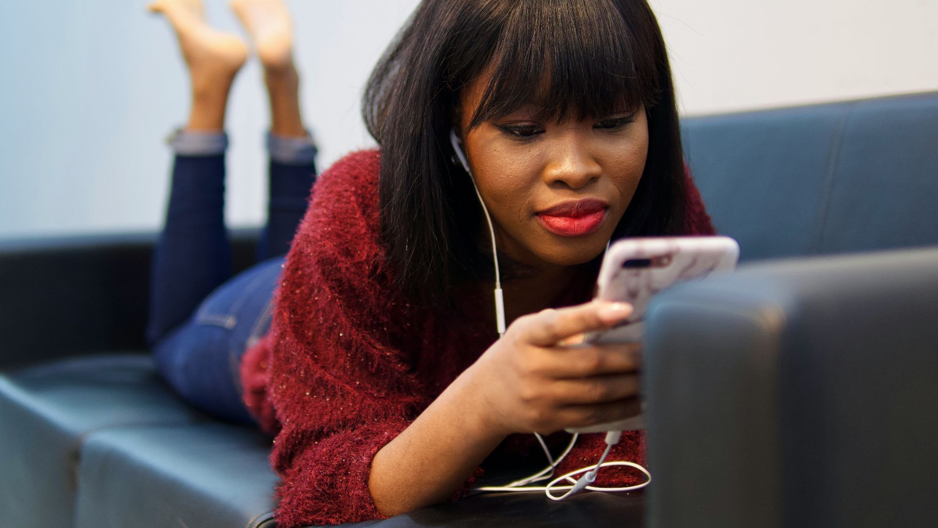 woman in blue sweater using white earbuds