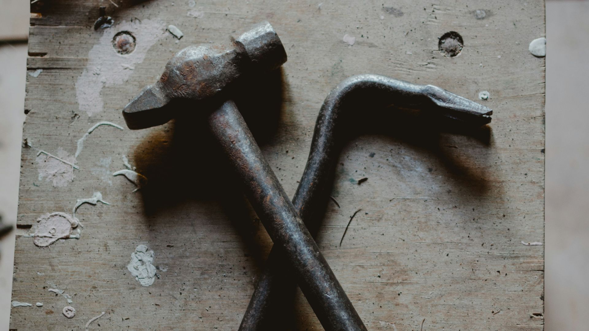 grey ball peen hammer and crow bar on brown wood
