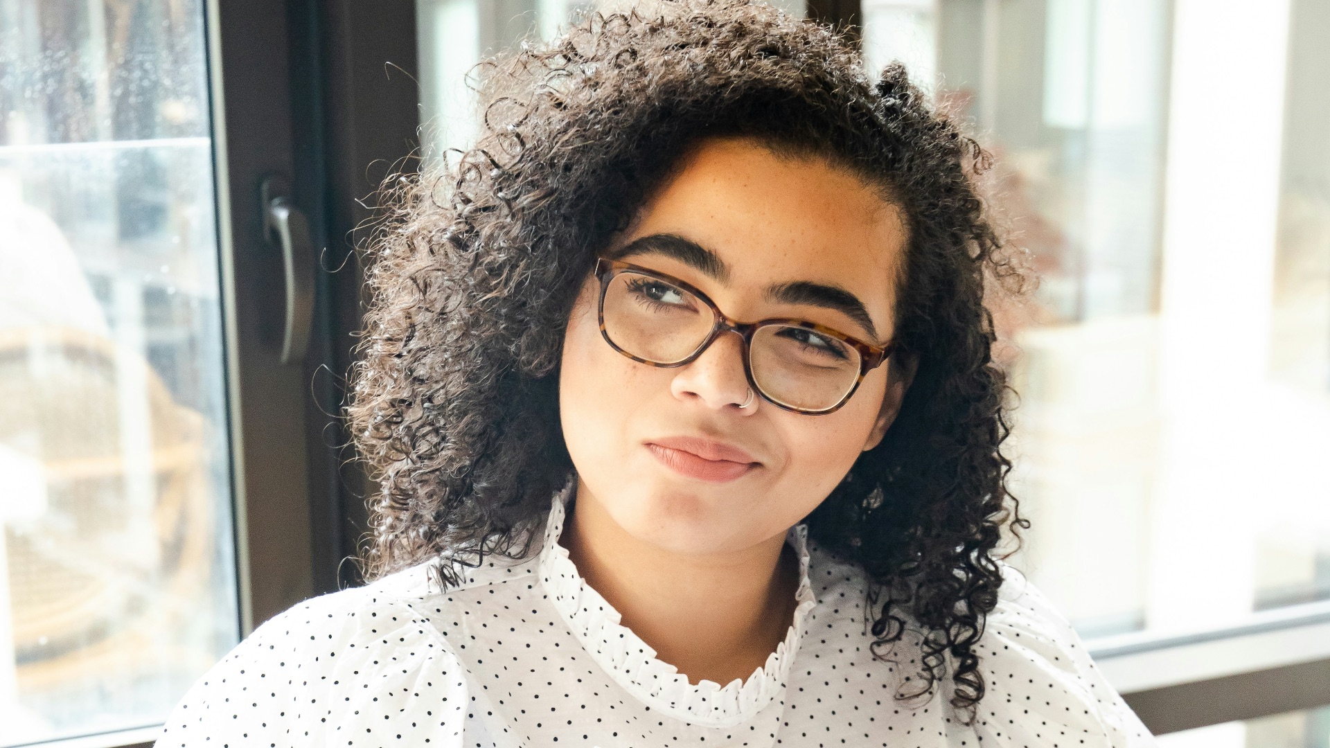 woman in white and black polka dot shirt holding blue and white book