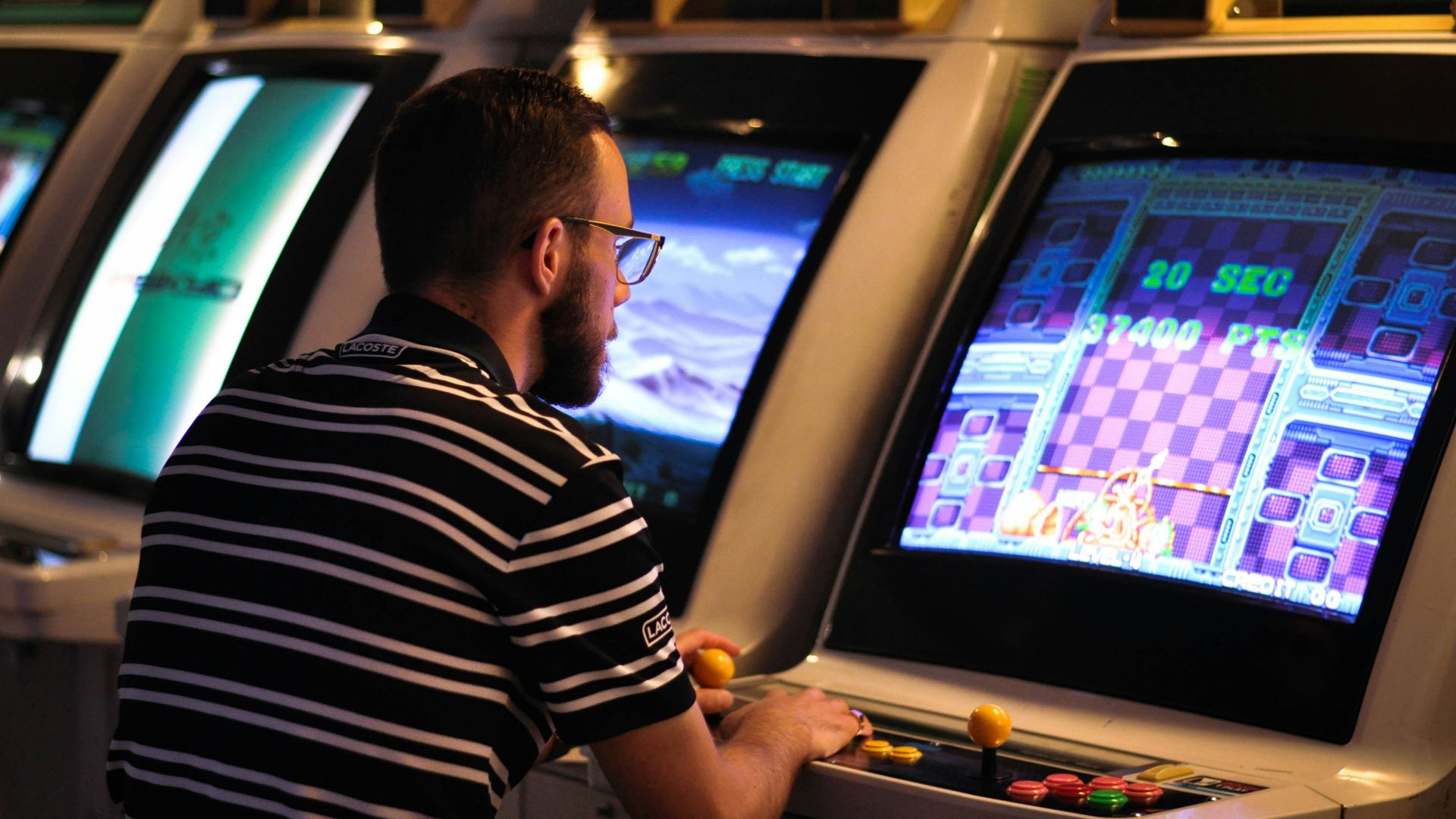 man in black and white striped shirt playing arcade game