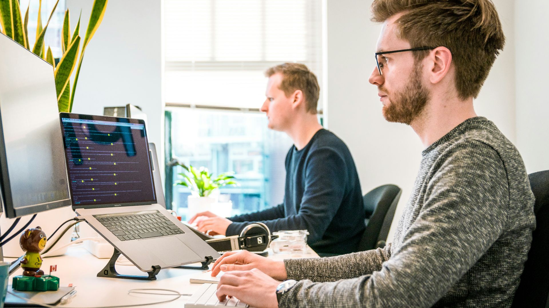 man sitting on chair wearing gray crew-neck long-sleeved shirt using Apple Magic Keyboard