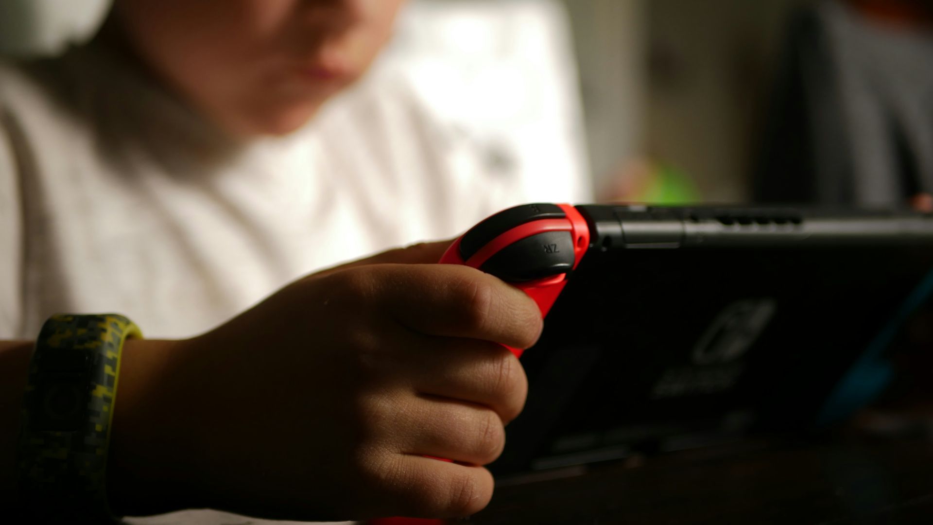 boy in white crew neck t-shirt holding black and red cordless device