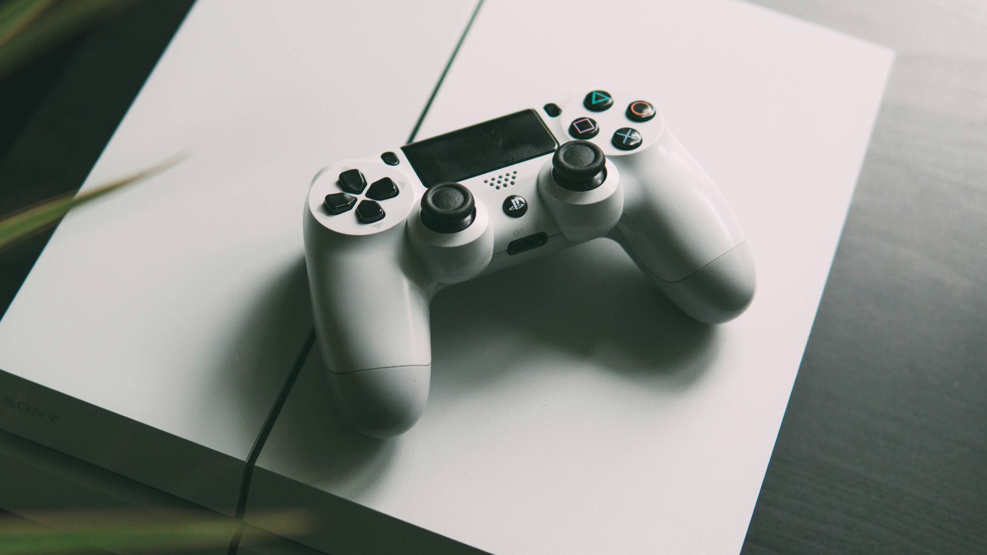 selective focus photography of white Sony PS4 console with wireless controller