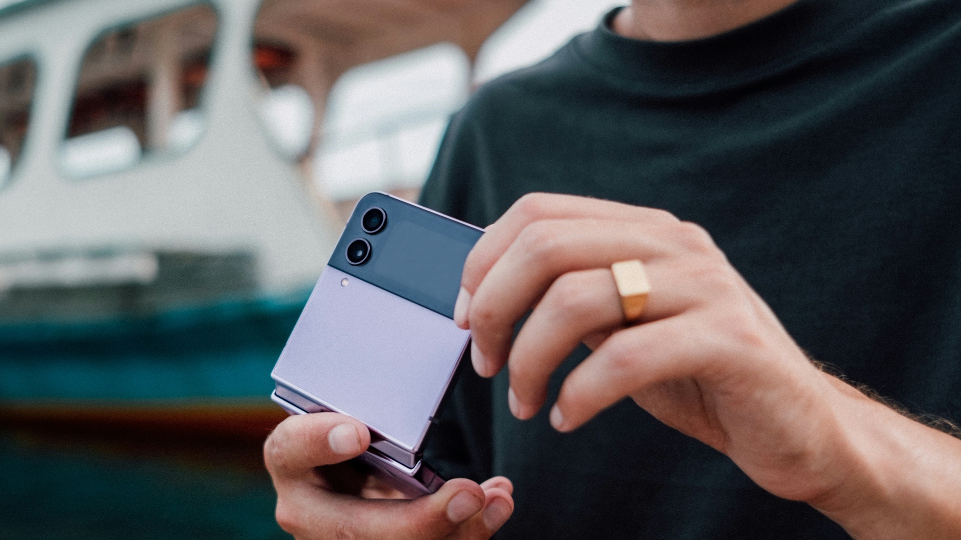 a man holding a cell phone in front of a boat