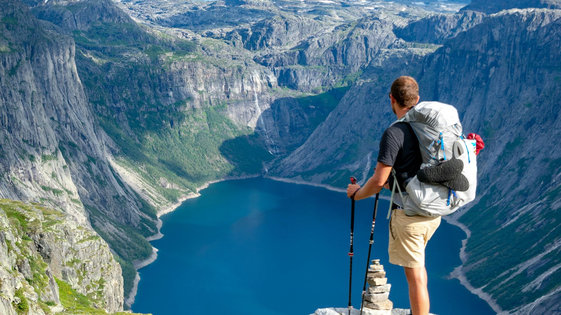 man standing on rock looking towards lake