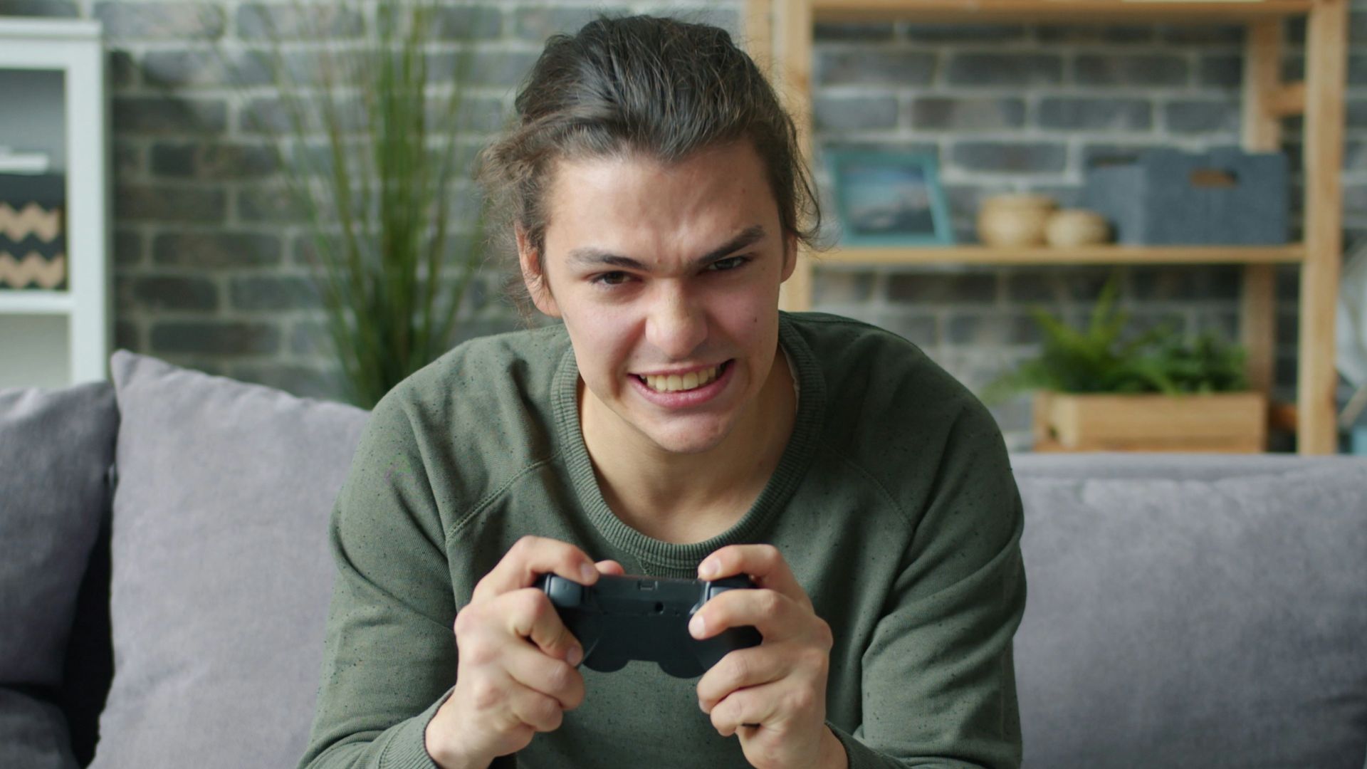 Young man intensely playing video games on couch