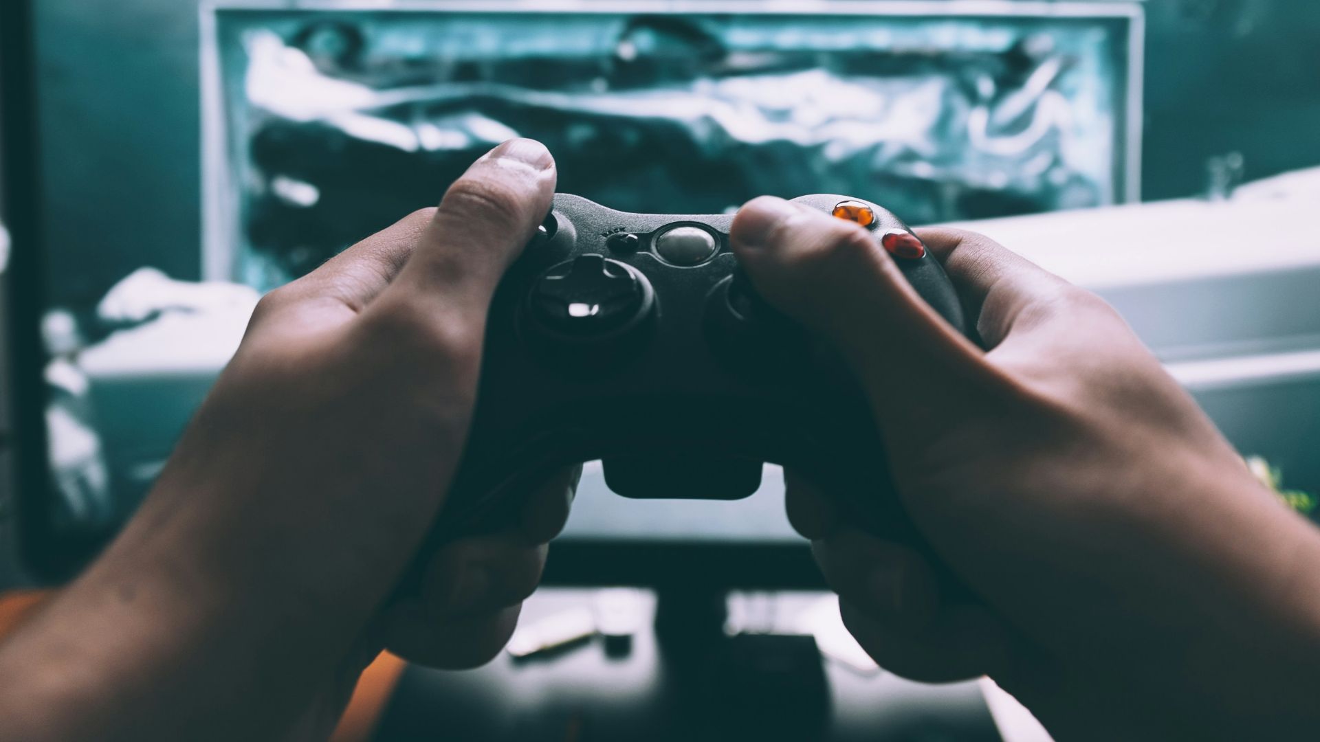 person holding game controller in-front of television