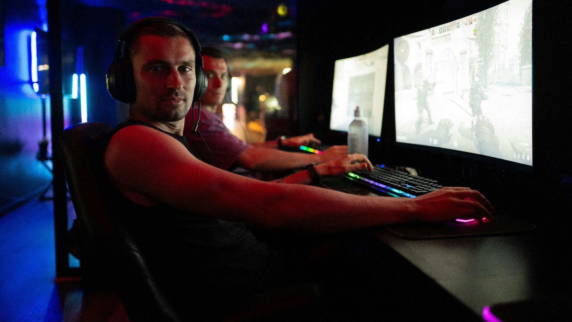 Men playing video games in a dimly lit room.