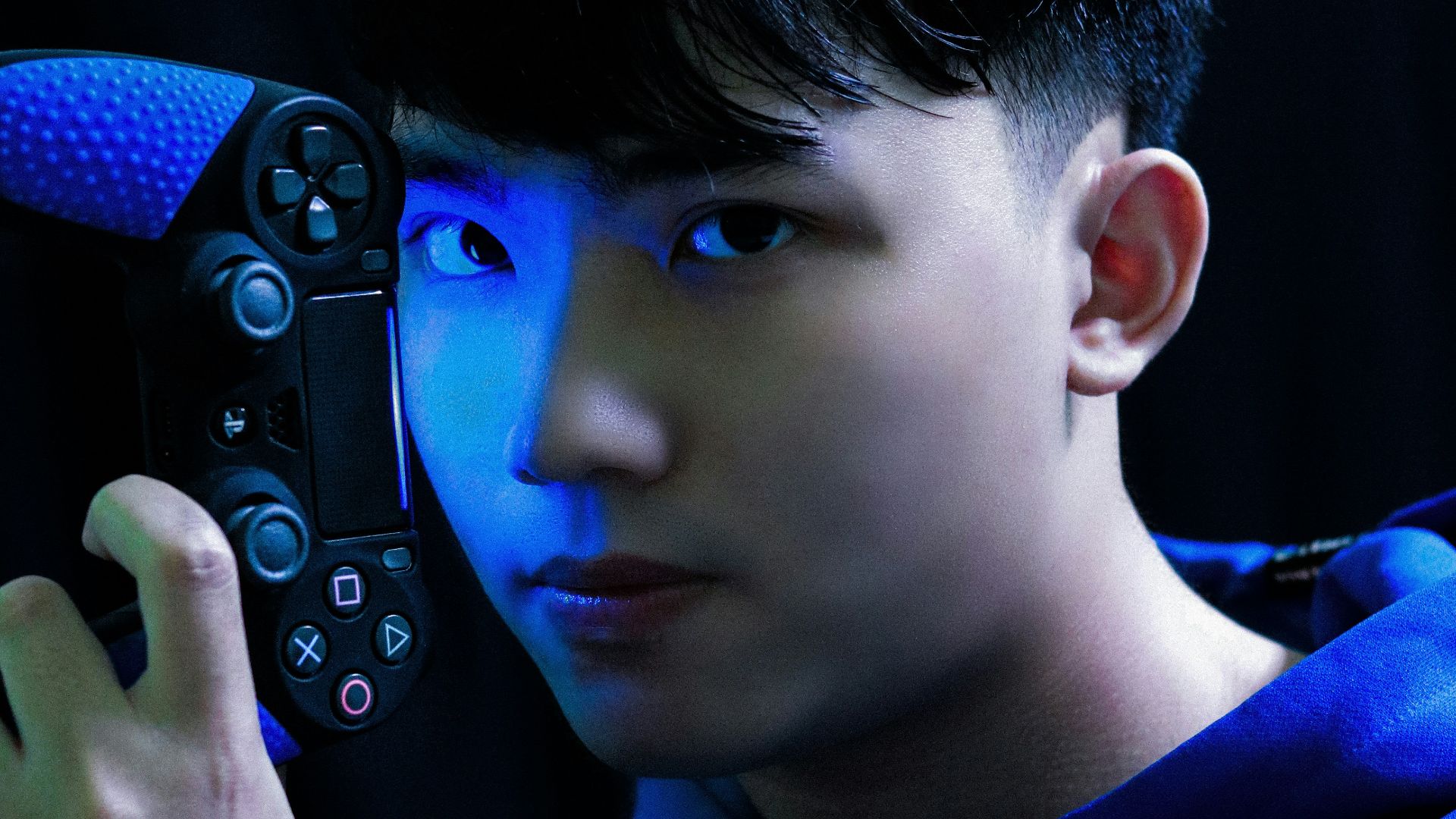 boy in blue long sleeve shirt holding black game controller