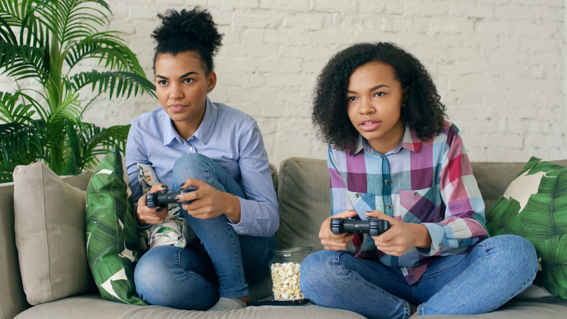 Two women playing video games on a couch.