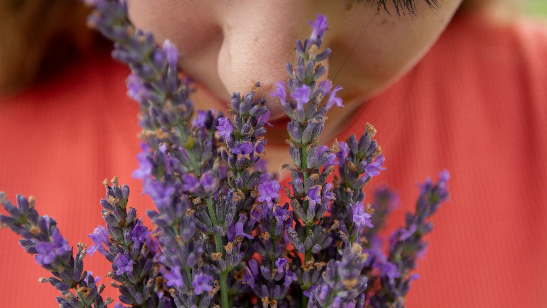 woman in orange shirt with purple flowers on her head