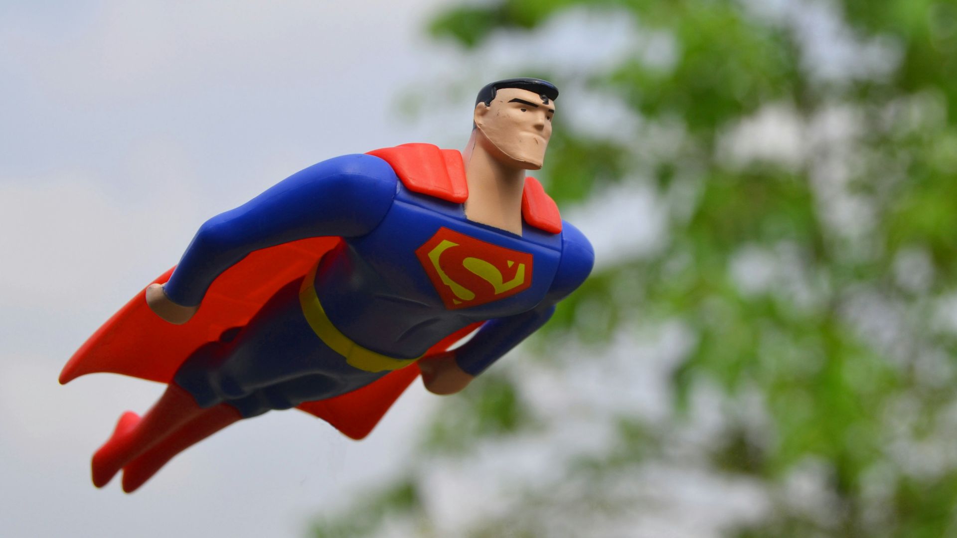 Superman flying near green grass