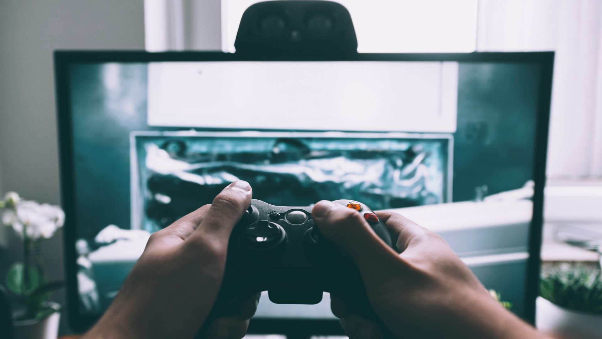 person holding game controller in-front of television