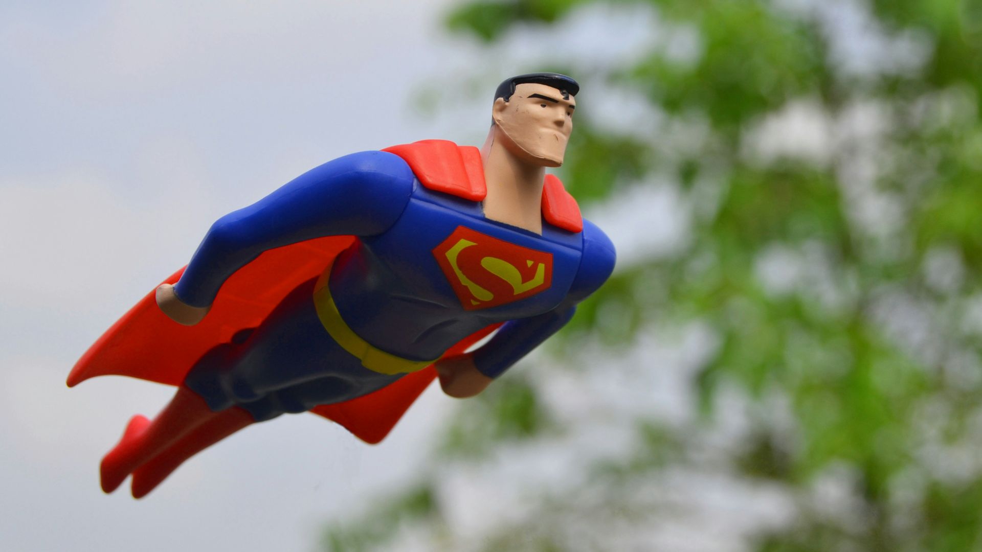 Superman flying near green grass