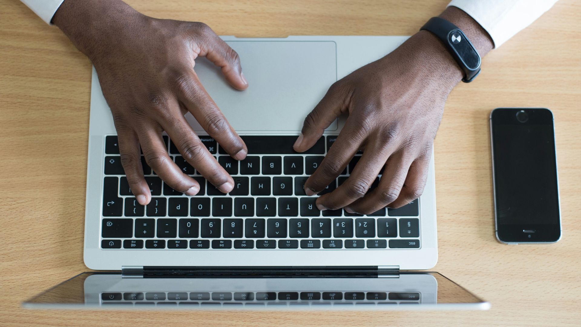 person's hand on MacBook near iPhone flat lay photography